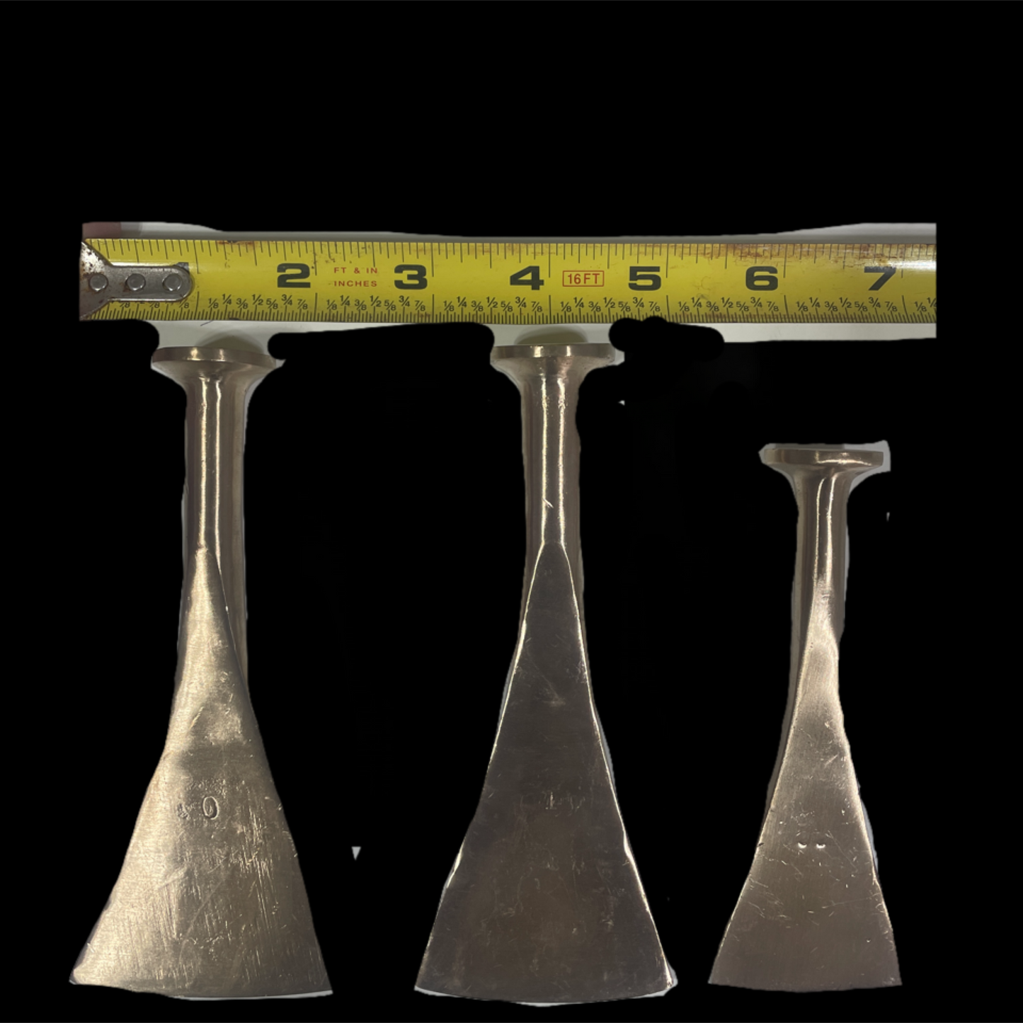 Three metal tools with a measuring tape above them on a black background