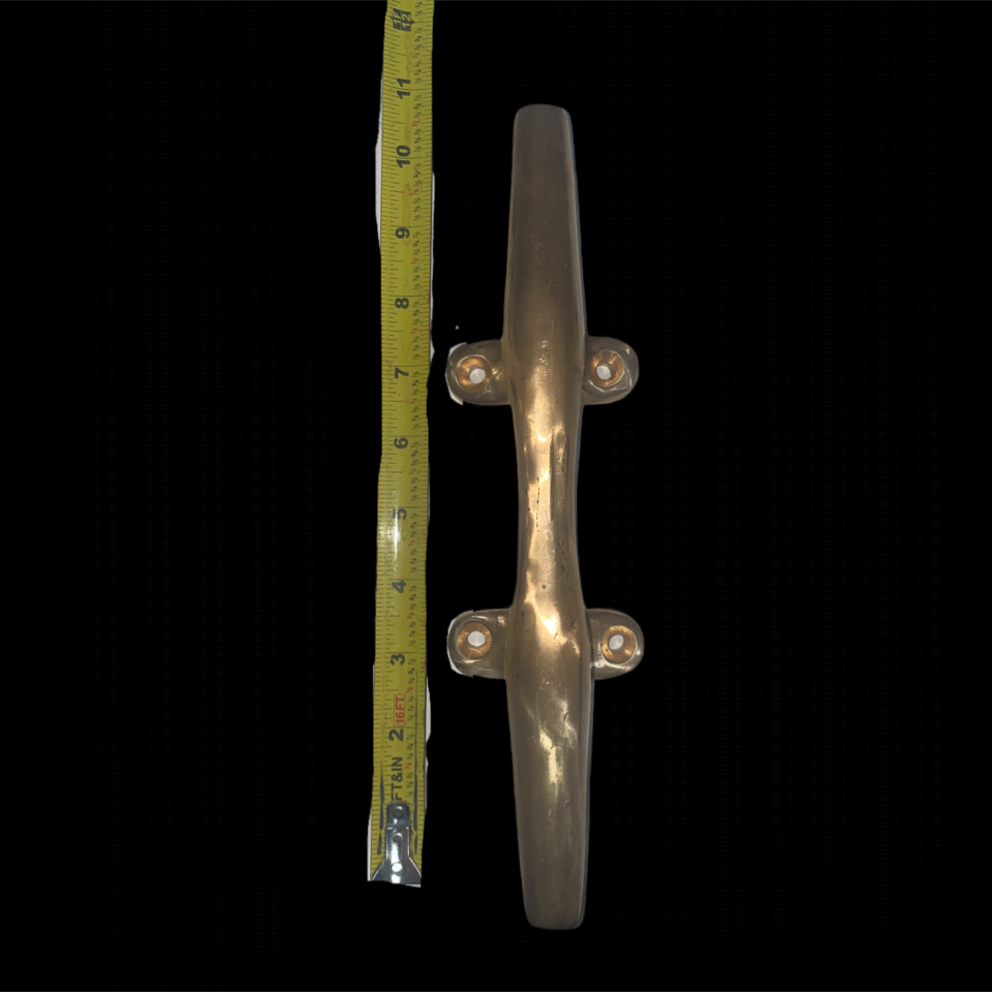 Metallic door handle with a tape measure for scale on a black background