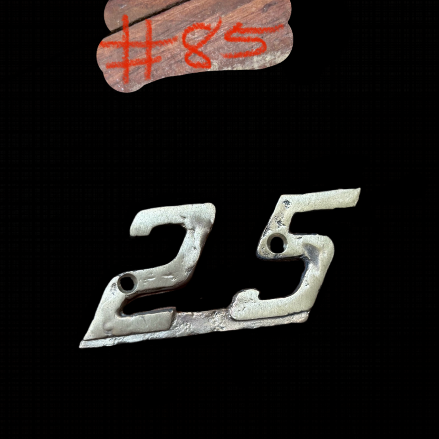 Metallic number '25' on a black background with '#85' in red above.
