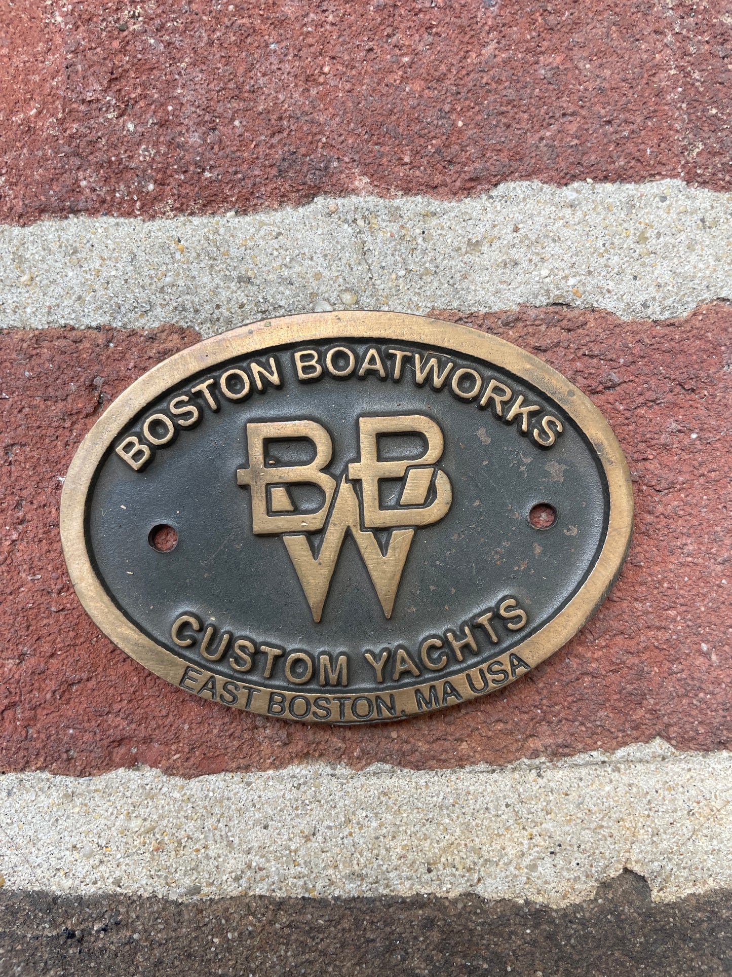 Bronze plaque with 'Boston Boatworks' logo on a textured surface