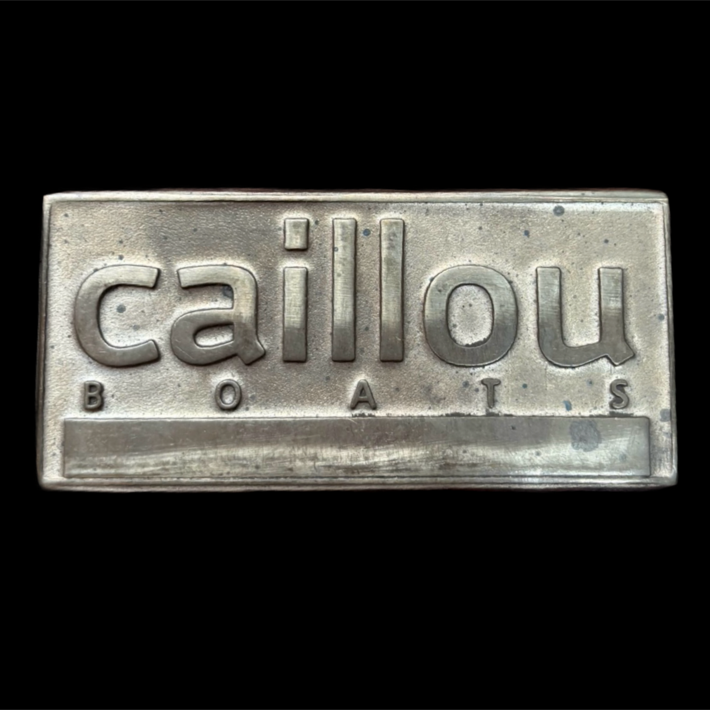 Metallic sign with 'caillou BOATS' text on a black background