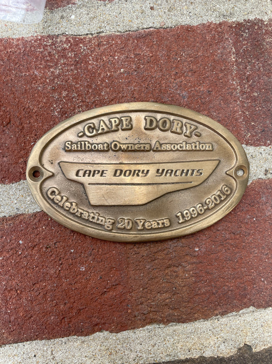Brass plaque with 'Cape Dory' branding on a textured surface
