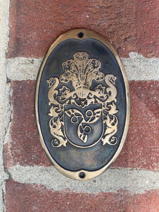 Decorative metal plaque with intricate design on a brick surface