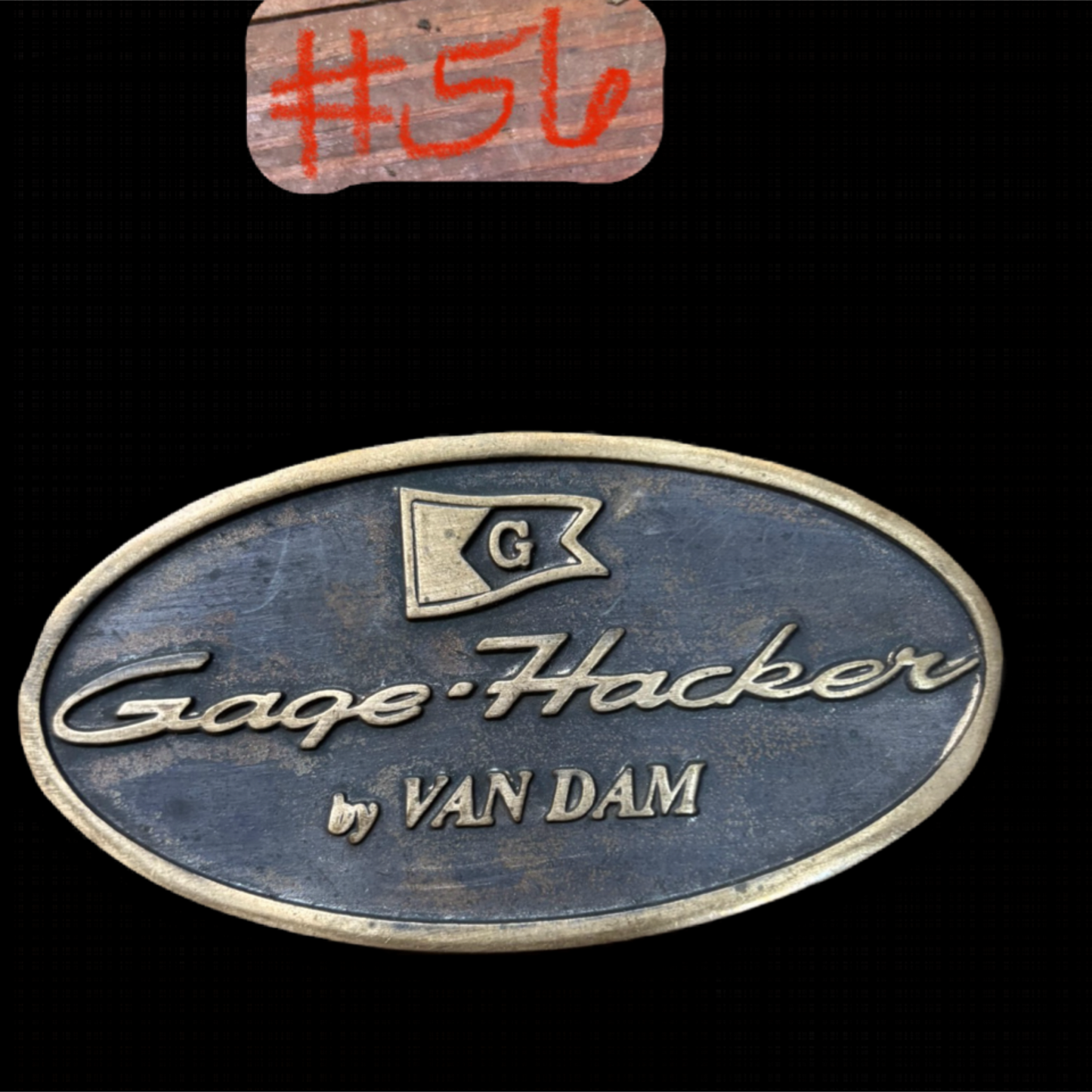 Metallic badge with 'Cage Hacker by Van Dam' text and logo on a black background