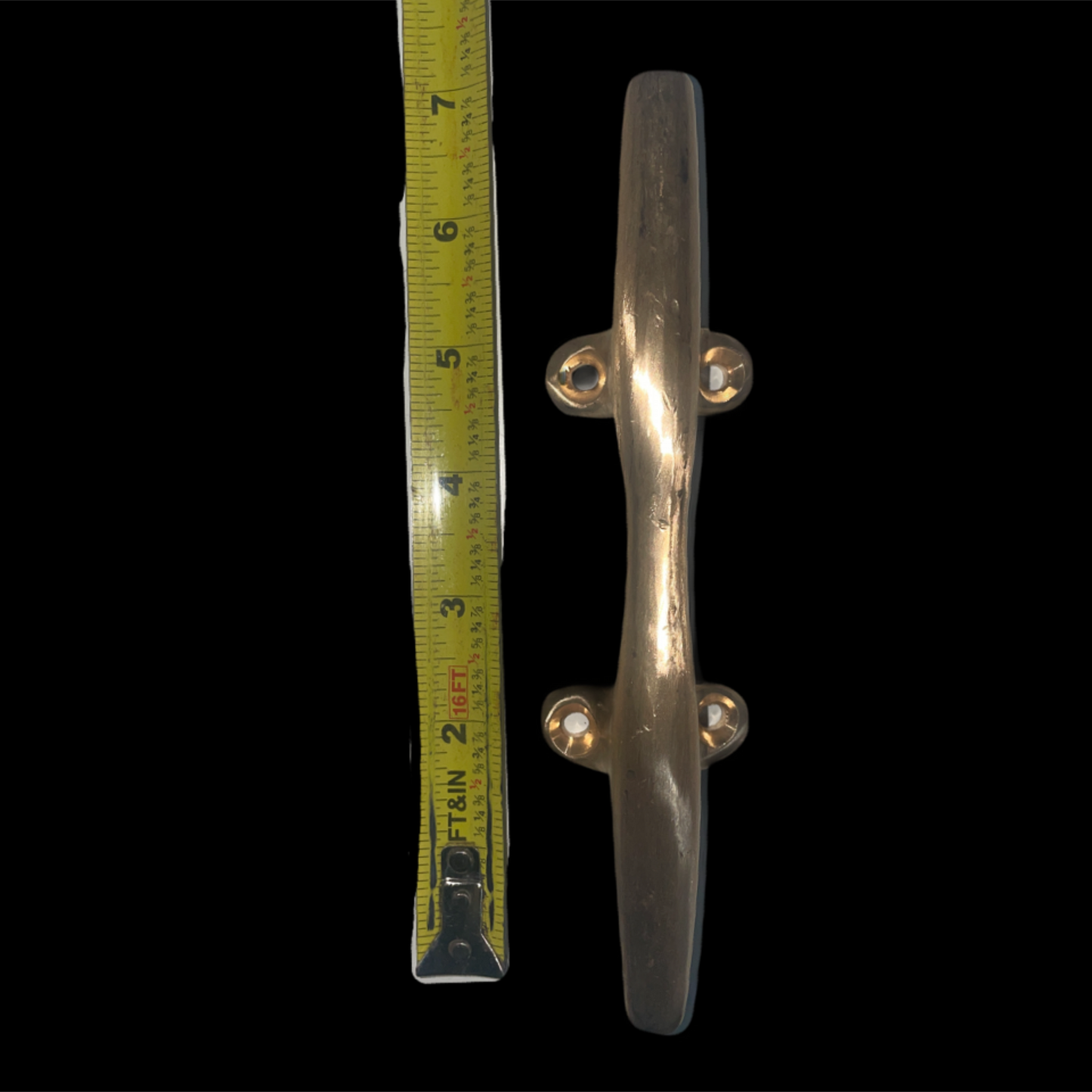 Metallic door handle next to a tape measure on a black background