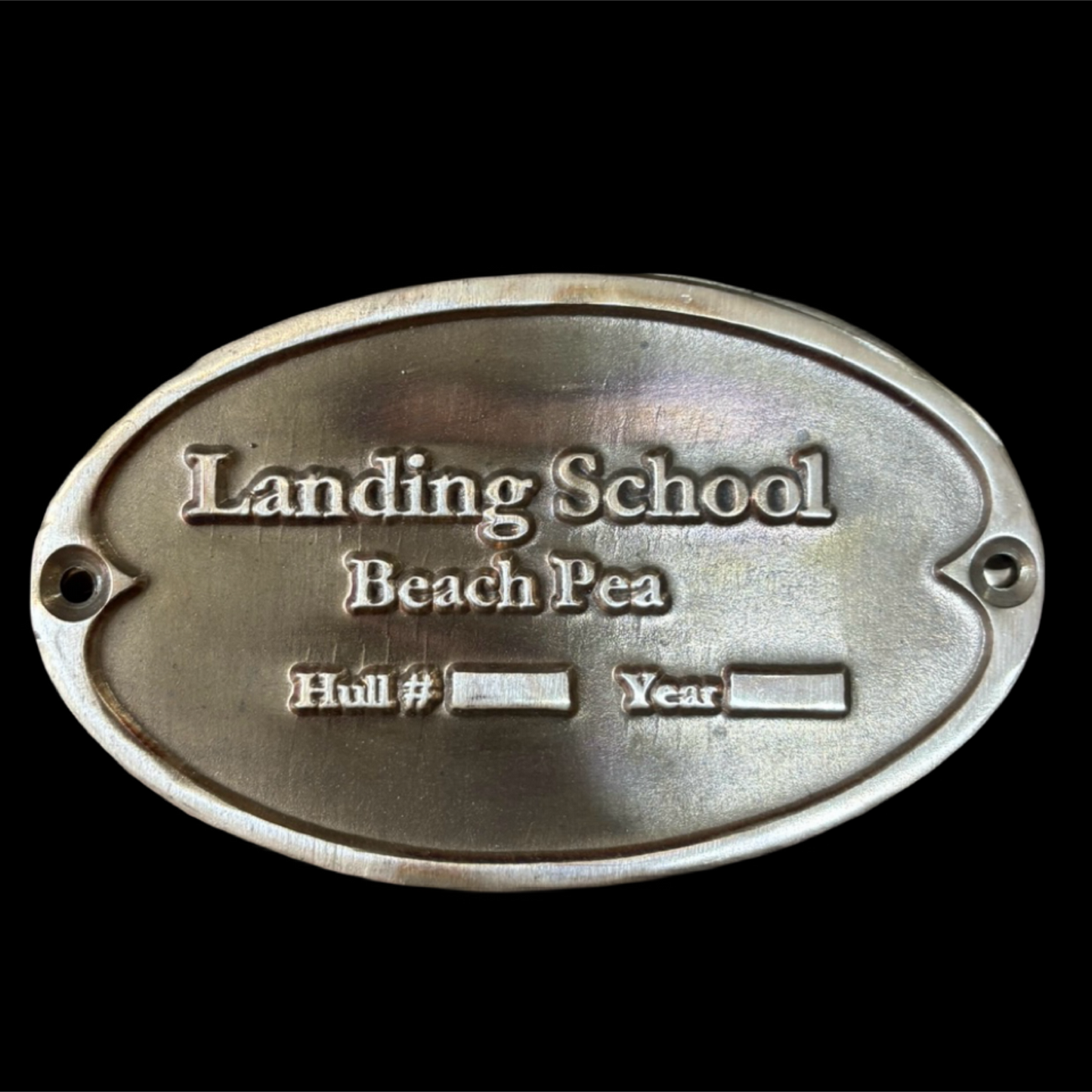 Metal plaque with 'Landing School Beach Pea' text on a black background