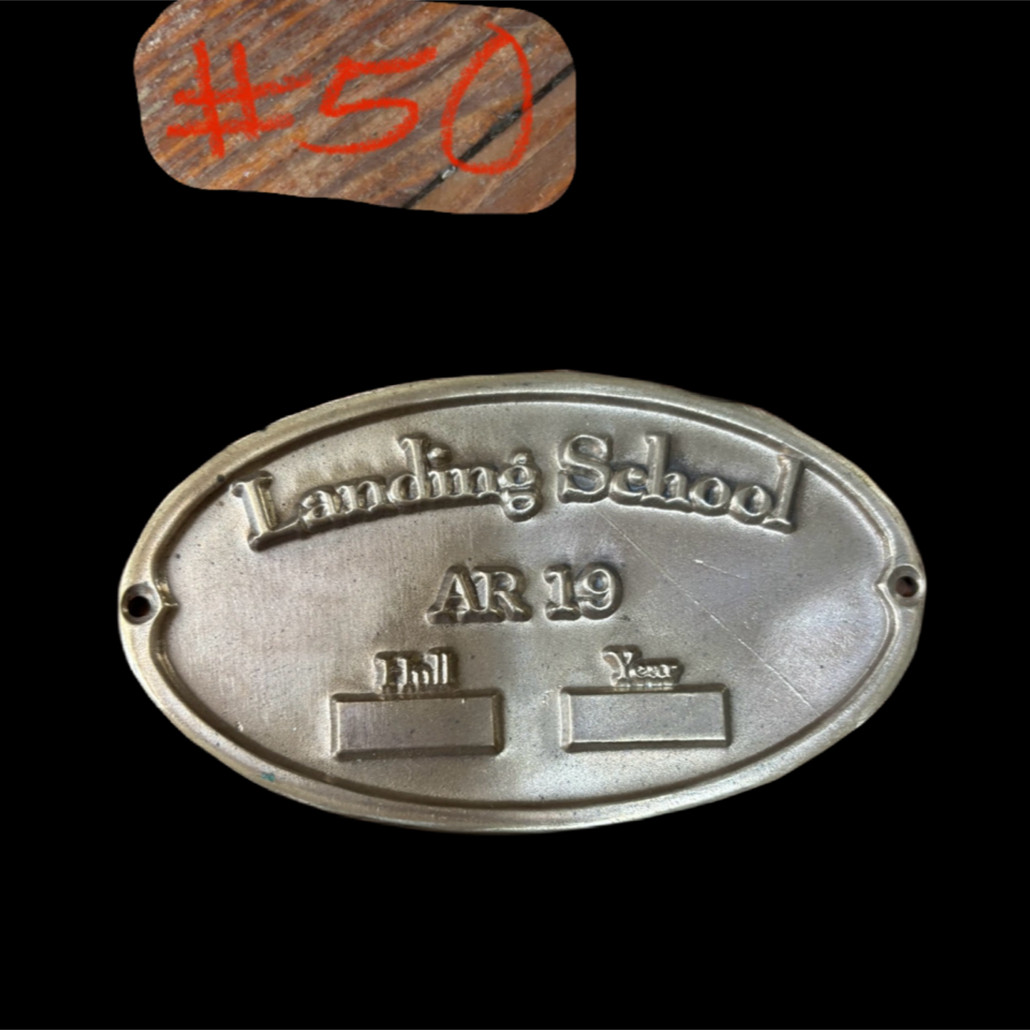 Metal plaque with 'Landing School AR 19' text on a black background