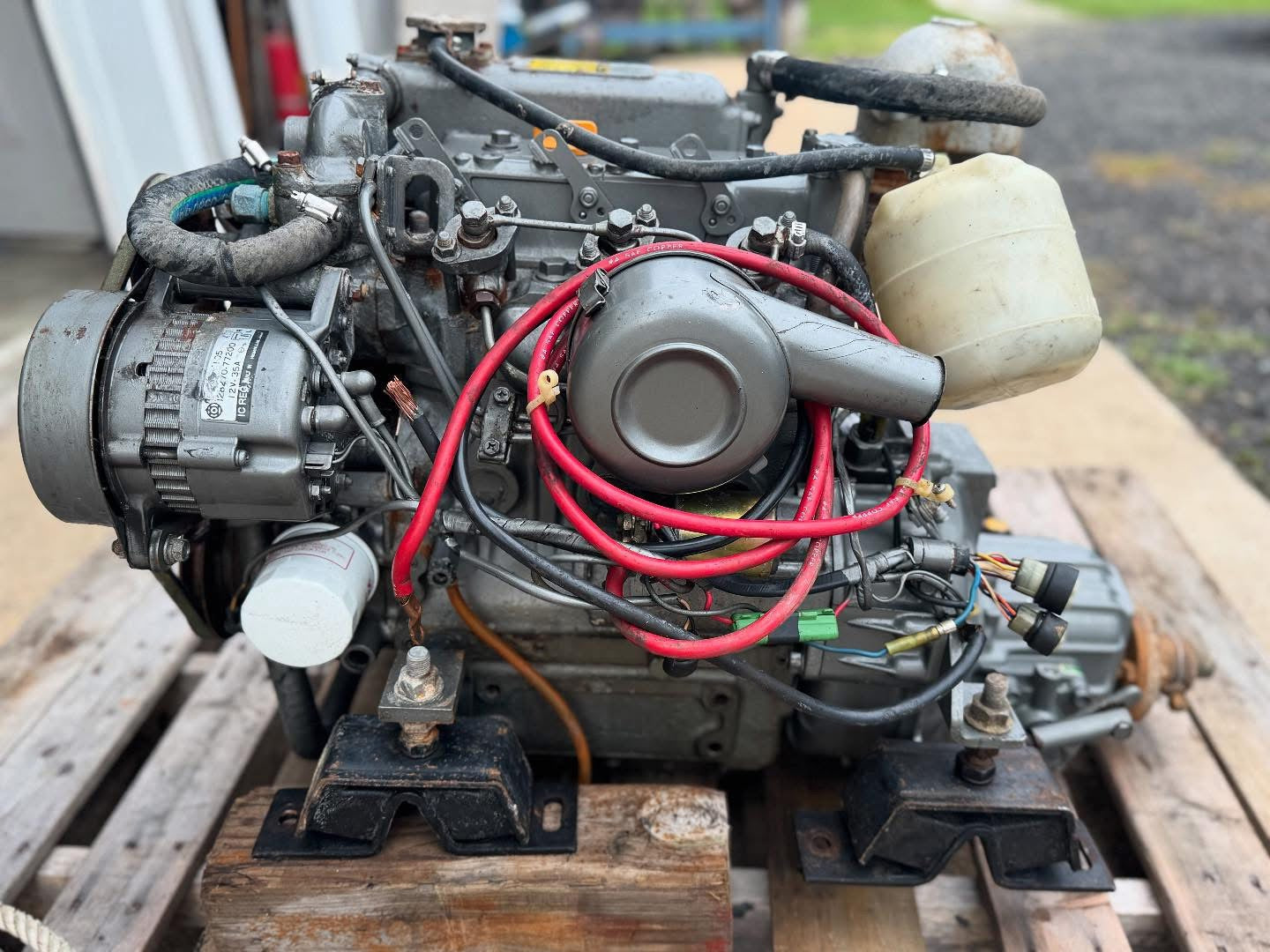 Marine engine on a wooden pallet with visible wiring and components.