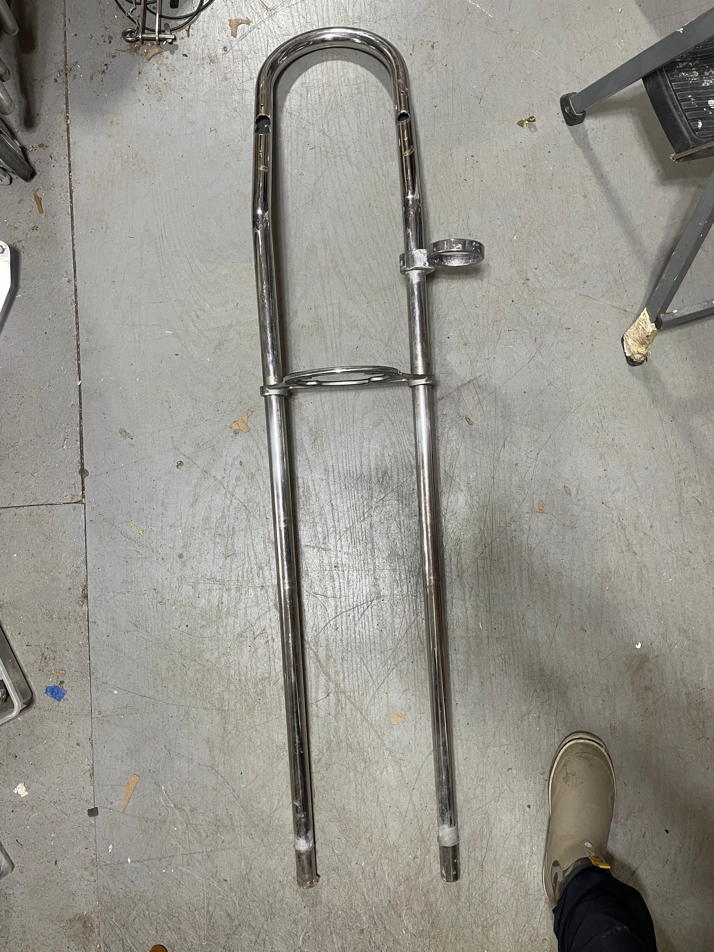 Chrome motorcycle fork on a concrete floor with a person's foot in the background