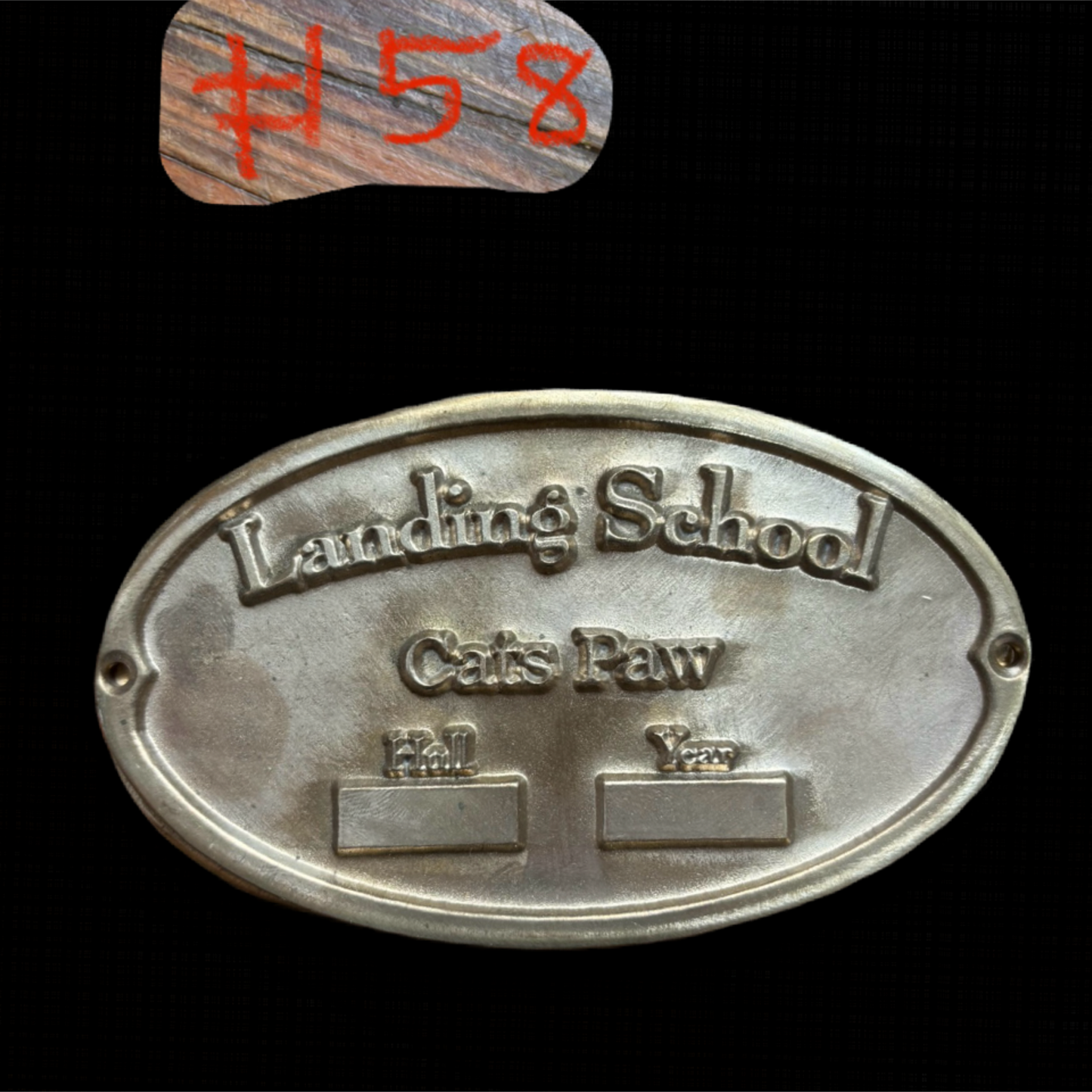Metal plaque with 'Landing School' text on a black background