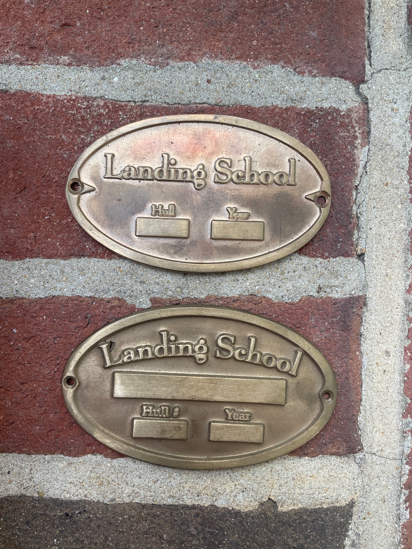 Two brass plaques on a brick surface with 'Landing School' engraved.