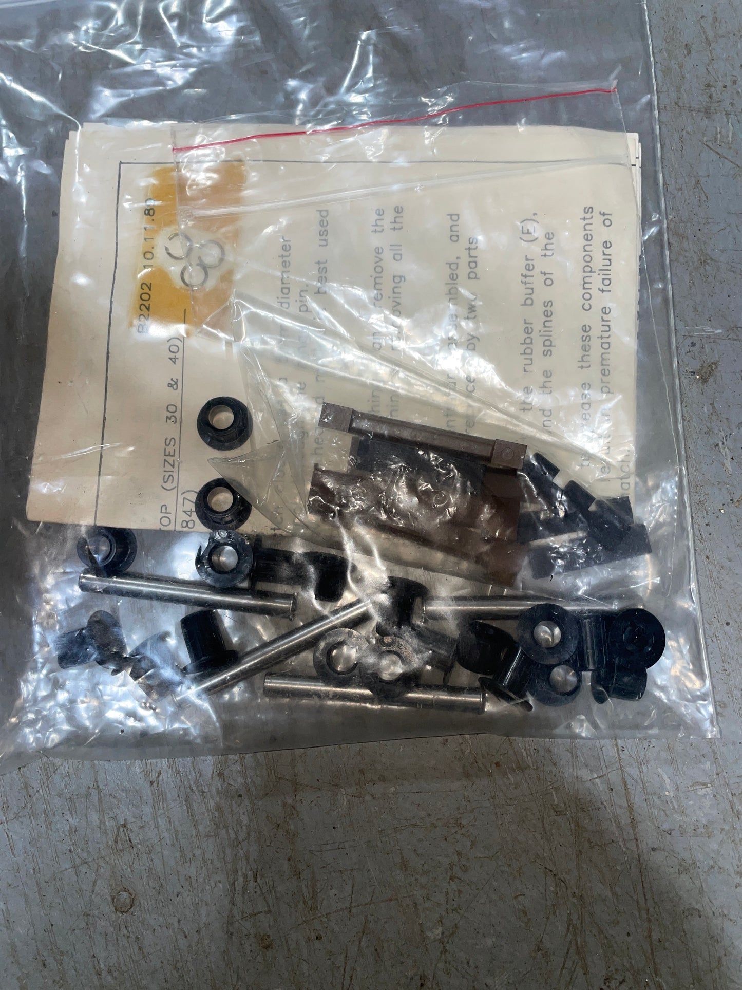 Mechanical parts in a clear plastic bag with a paper label on a metal surface