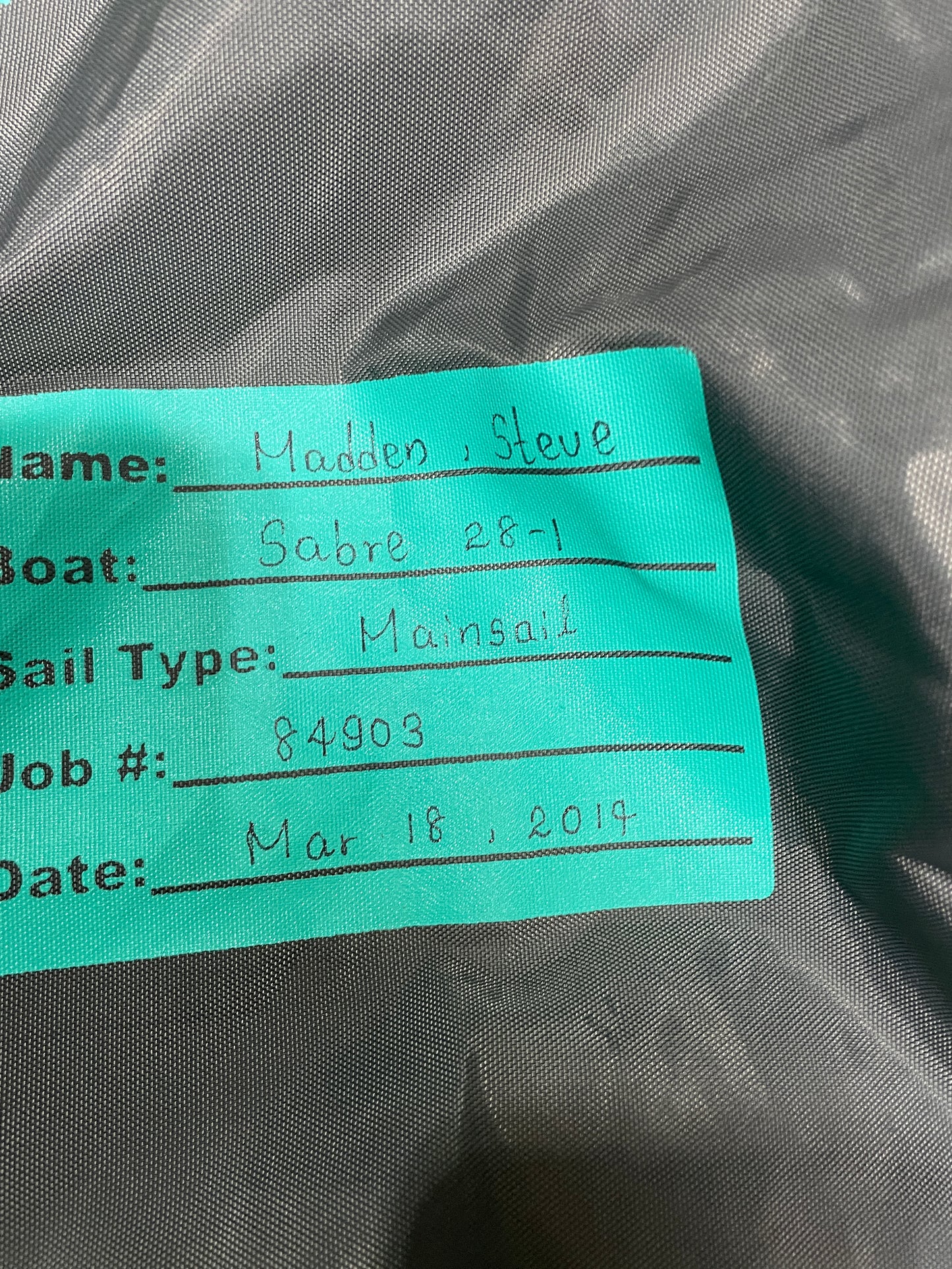 Close-up of a teal tag with text on a dark fabric background