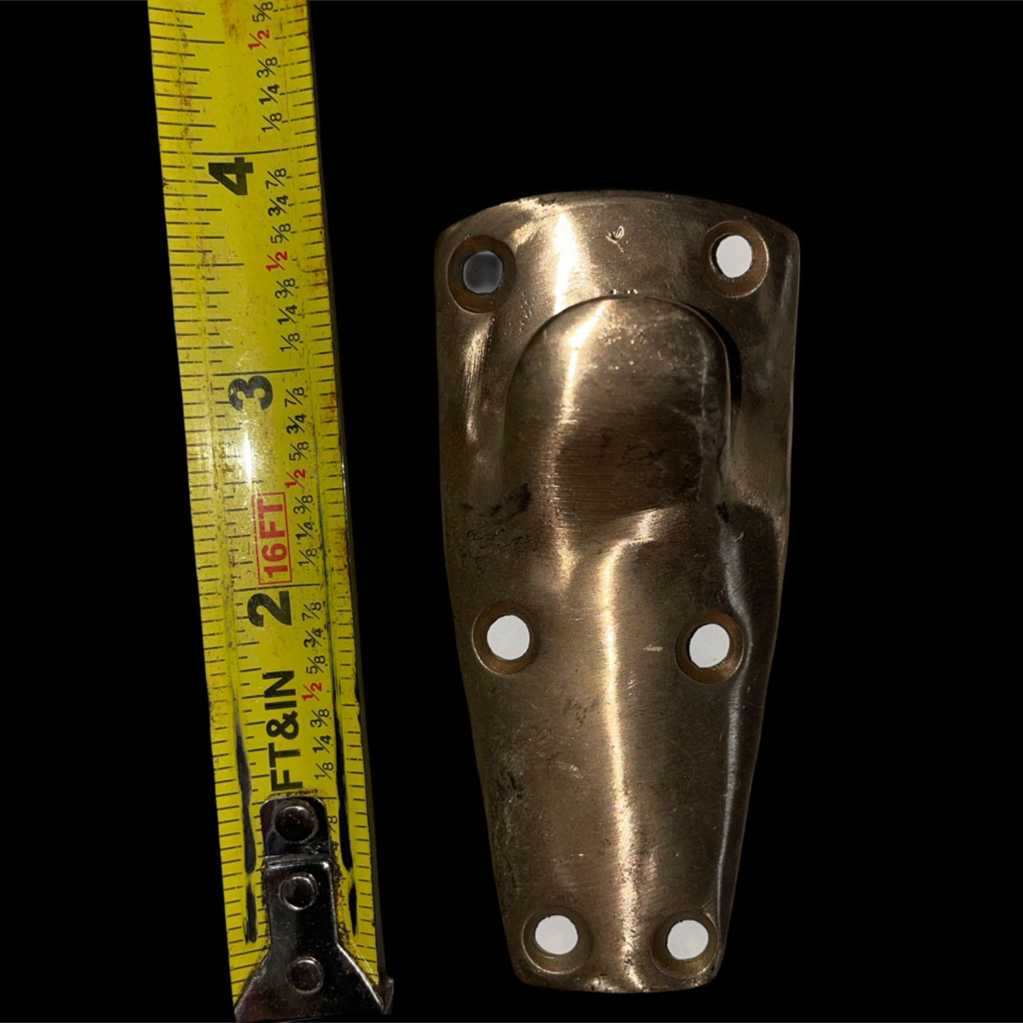Bronze metal bracket with measurement tape on a black background
