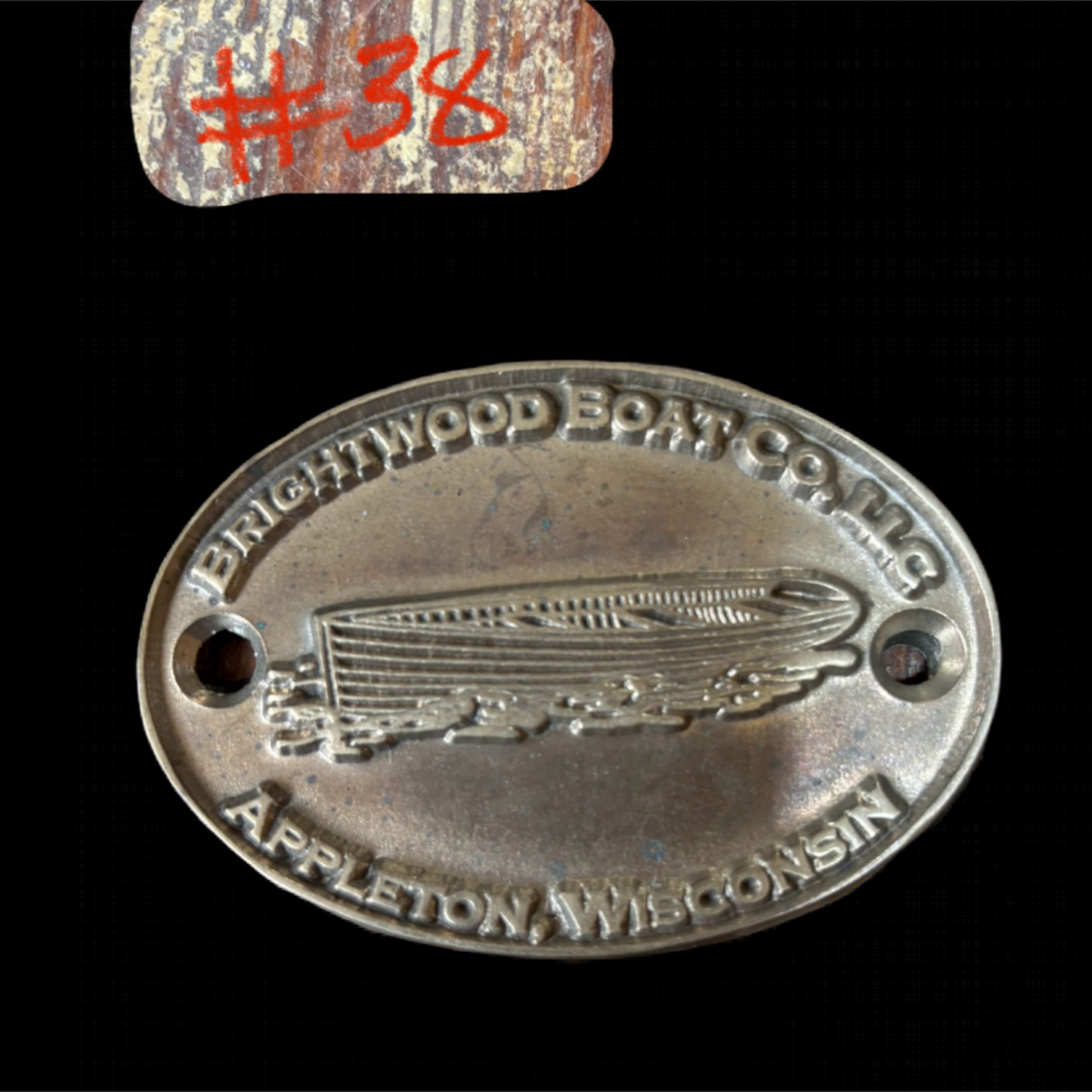 Metal badge with 'Brightwood Boat Co.' branding and a zeppelin illustration on a black background.