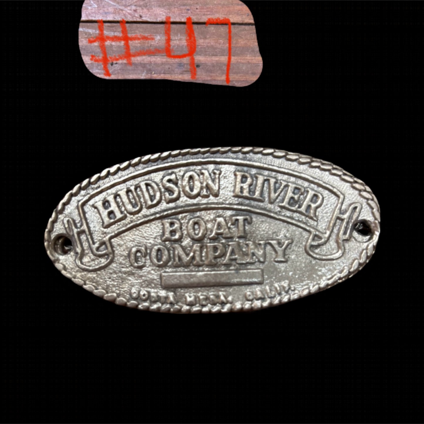 Metal plaque with 'Hudson River Boat Company' text on a black background