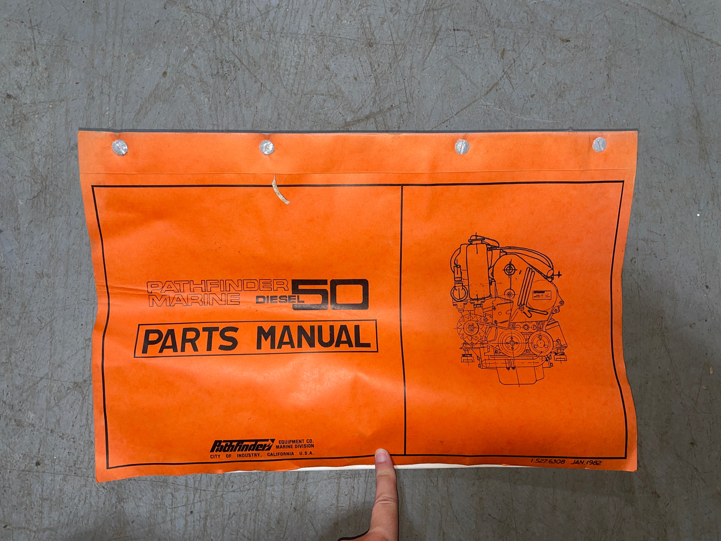 Orange parts manual for Caterpillar diesel engines on a gray surface