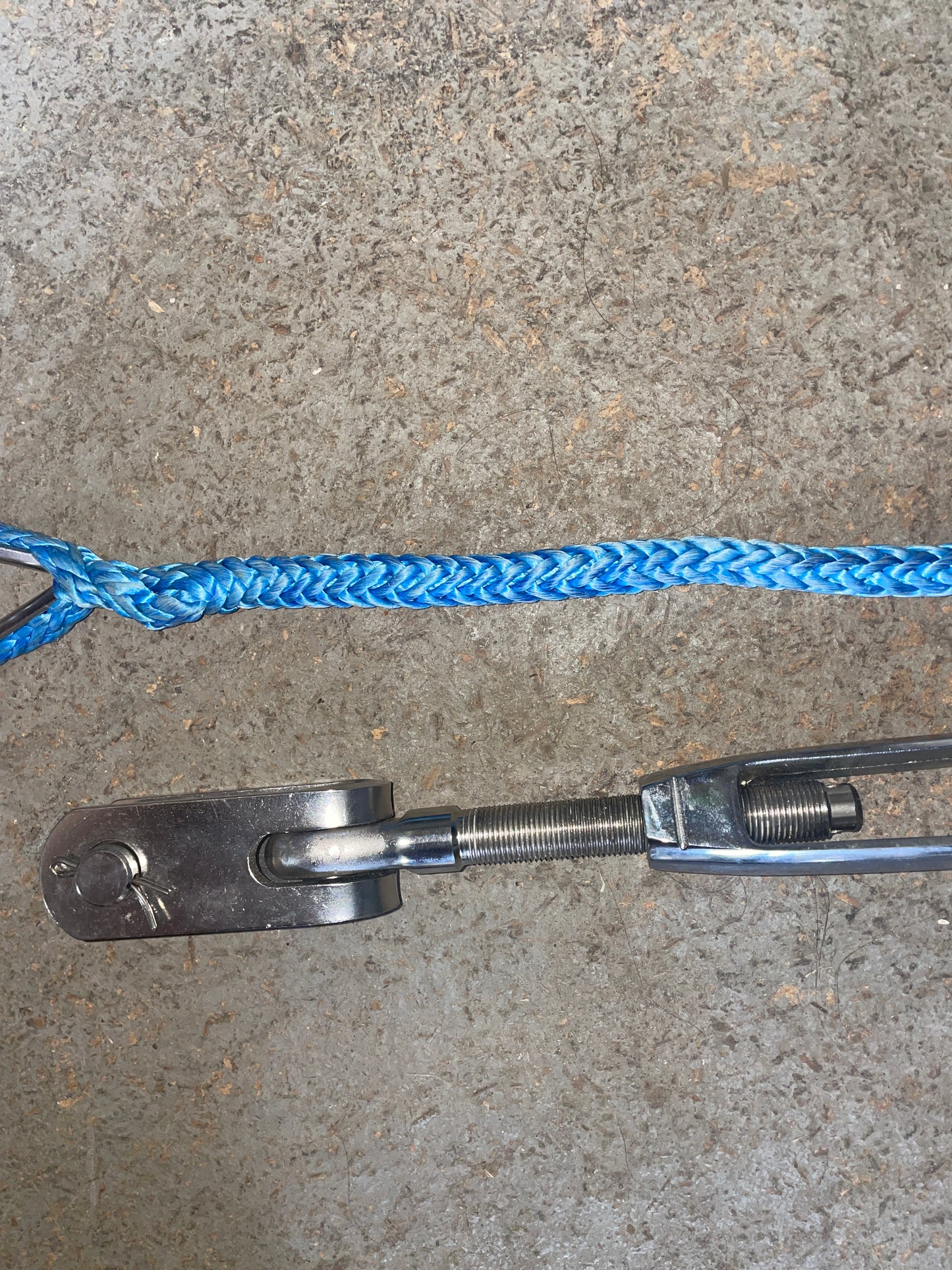 Blue rope attached to a metal pulley system on a concrete surface