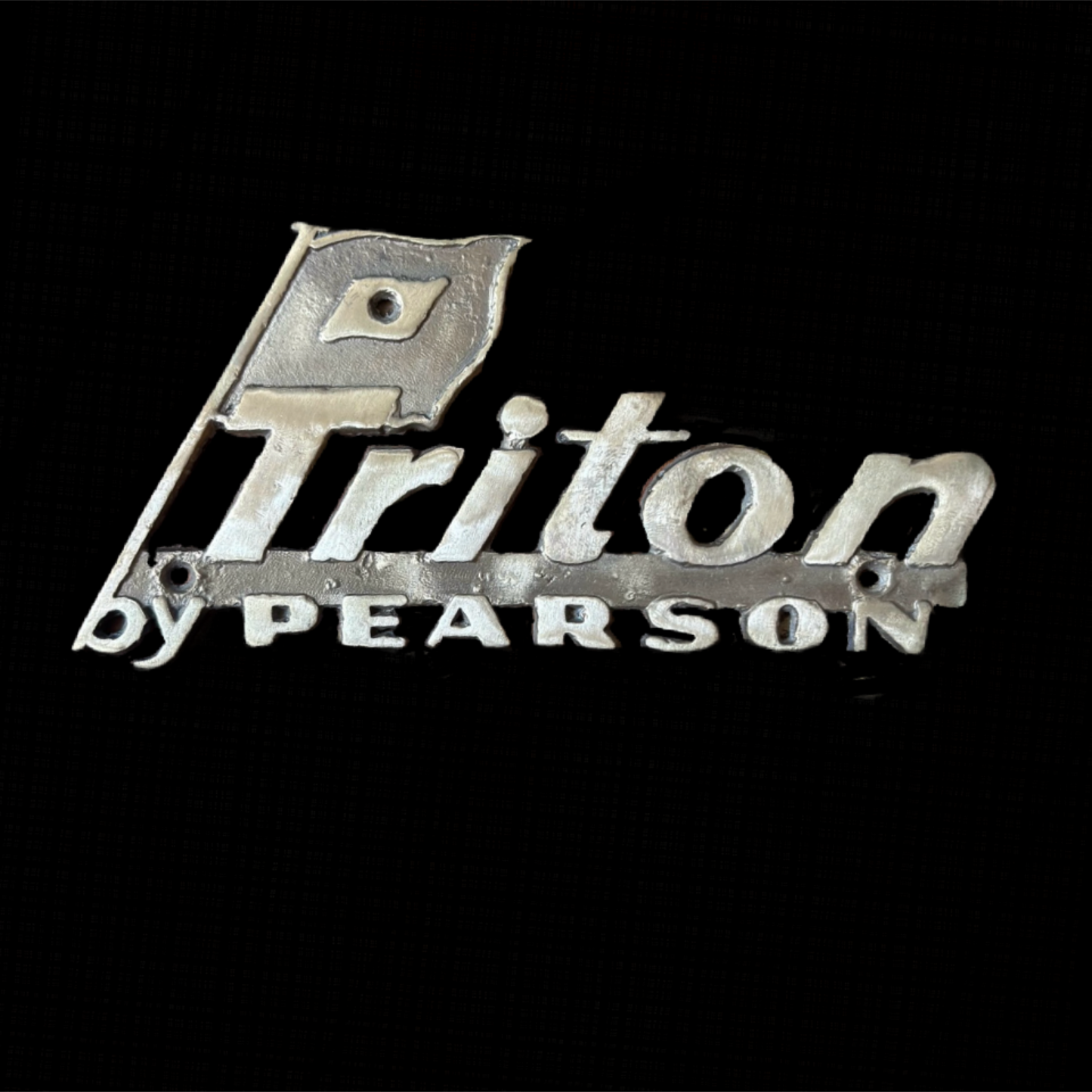 Metallic 'Triton by Pearson' logo on a black background