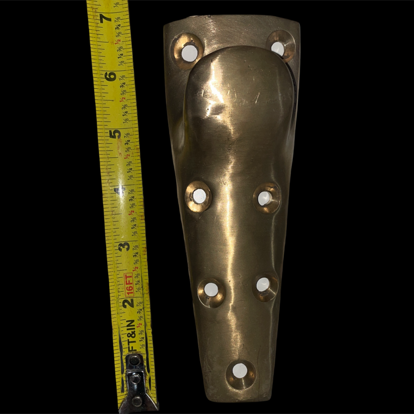 Brass door handle with measurement tape on a black background