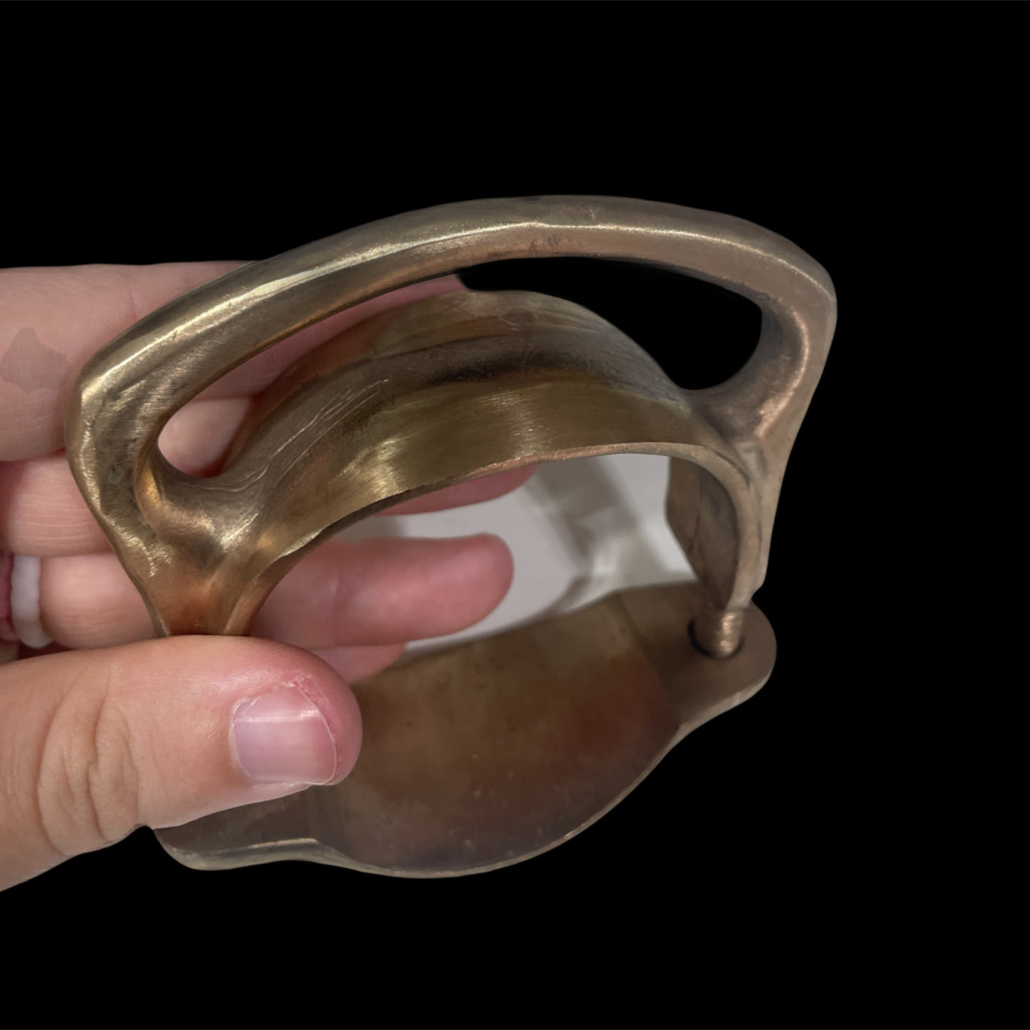 Hand holding a metallic object with a black background