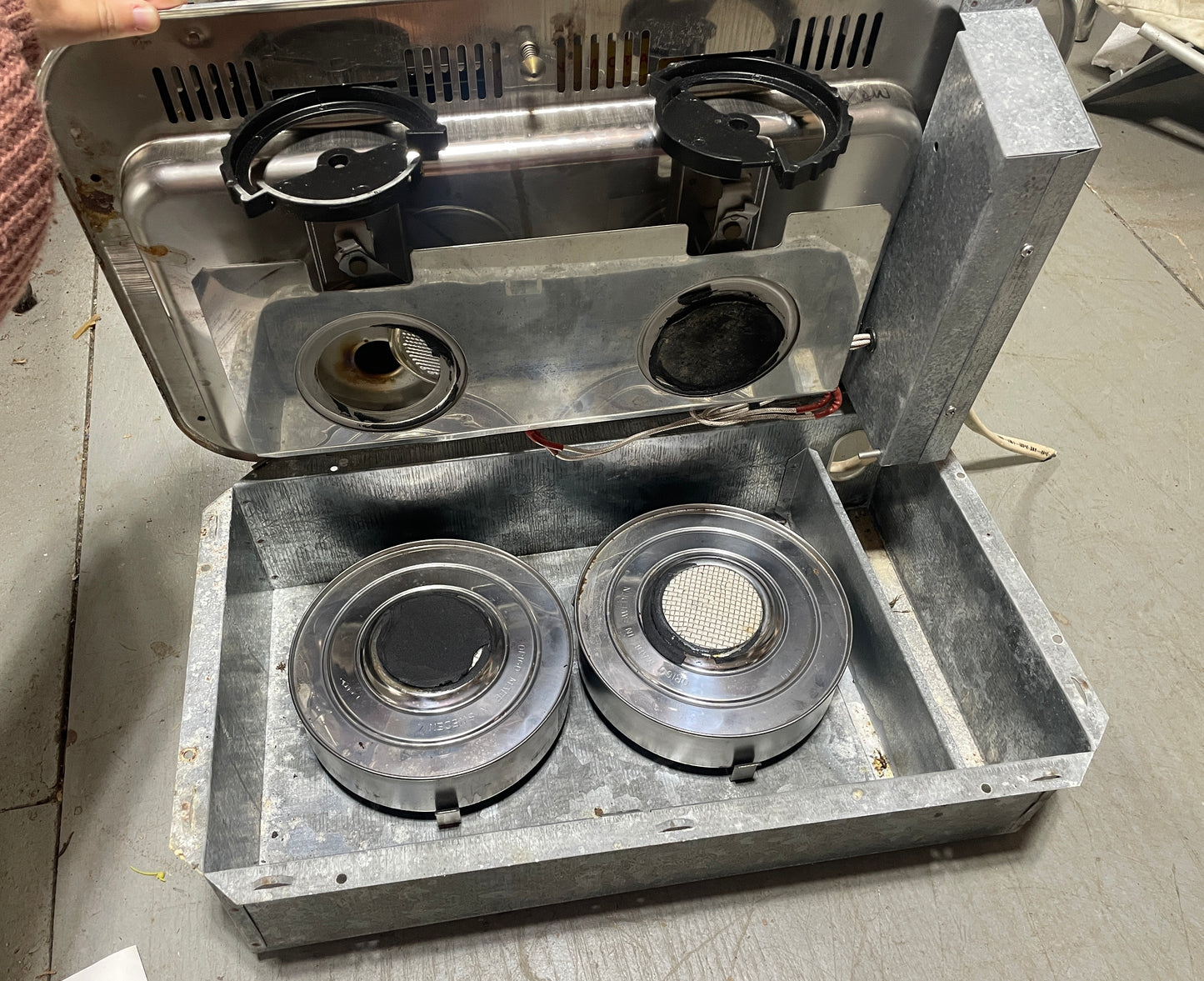 Metal stove top with four burners on a concrete floor