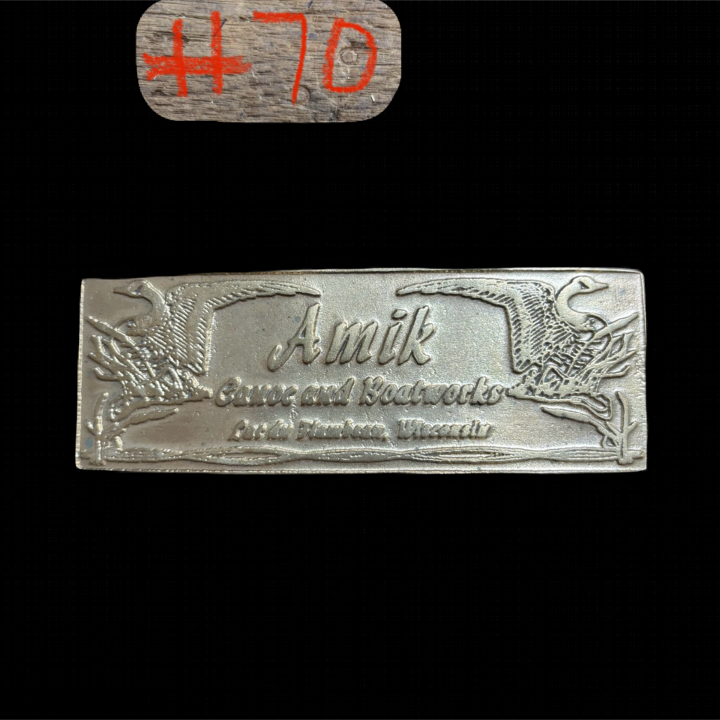 bronze Amik game and boat works logo on a black background