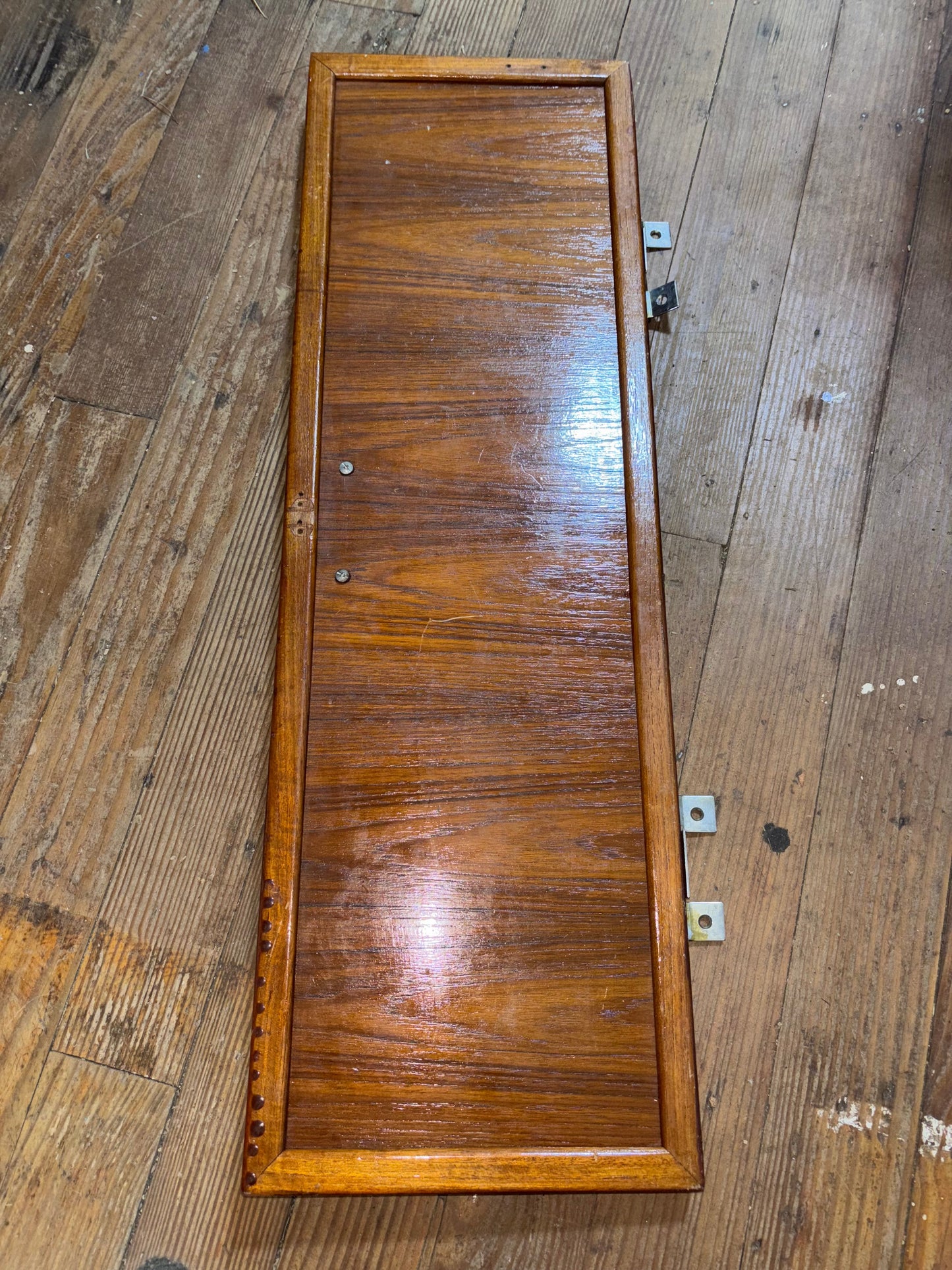 Wooden panel with a rectangular cutout on a wooden wall.