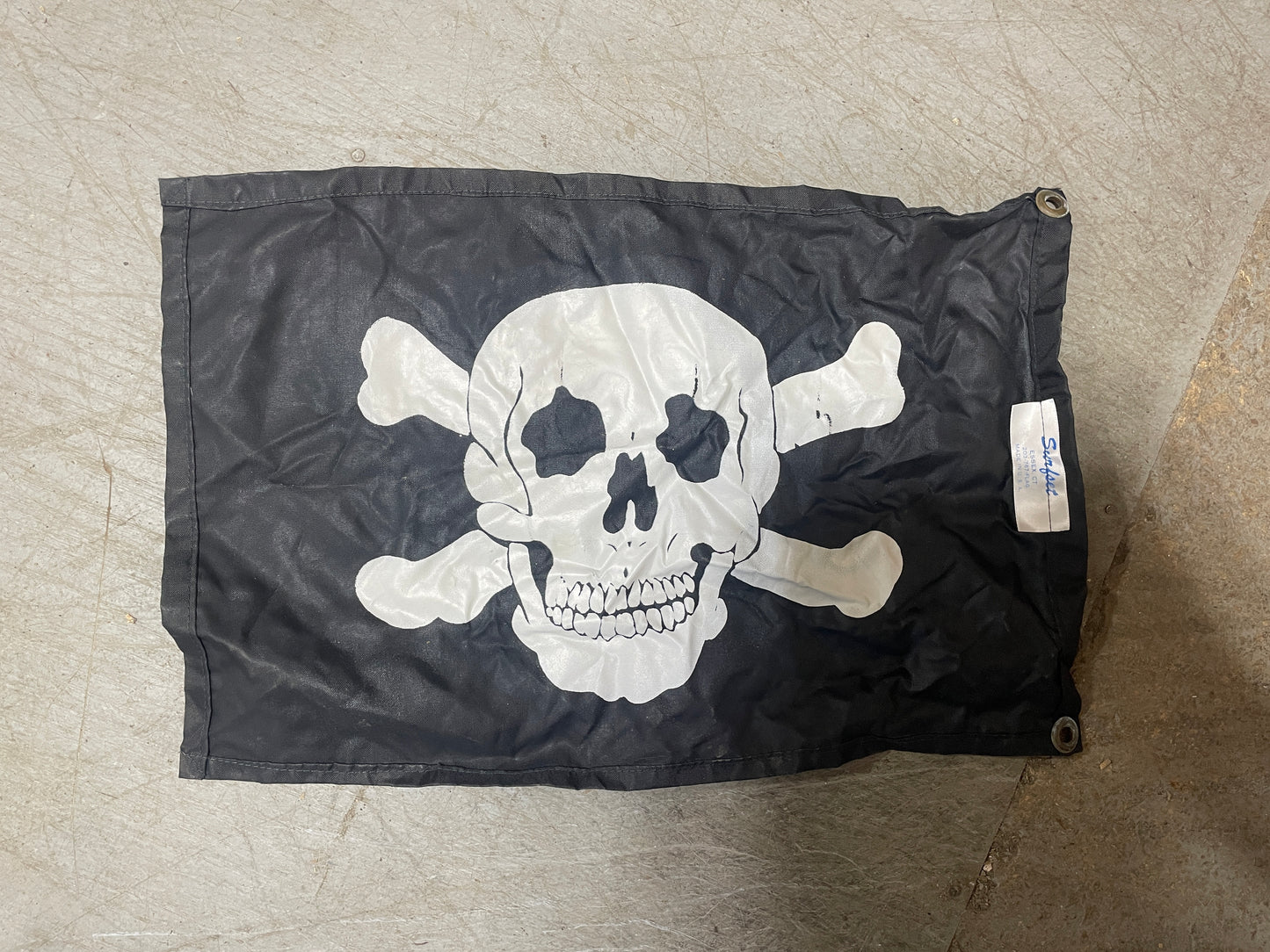 Black flag with a white skull and crossbones design on a textured surface