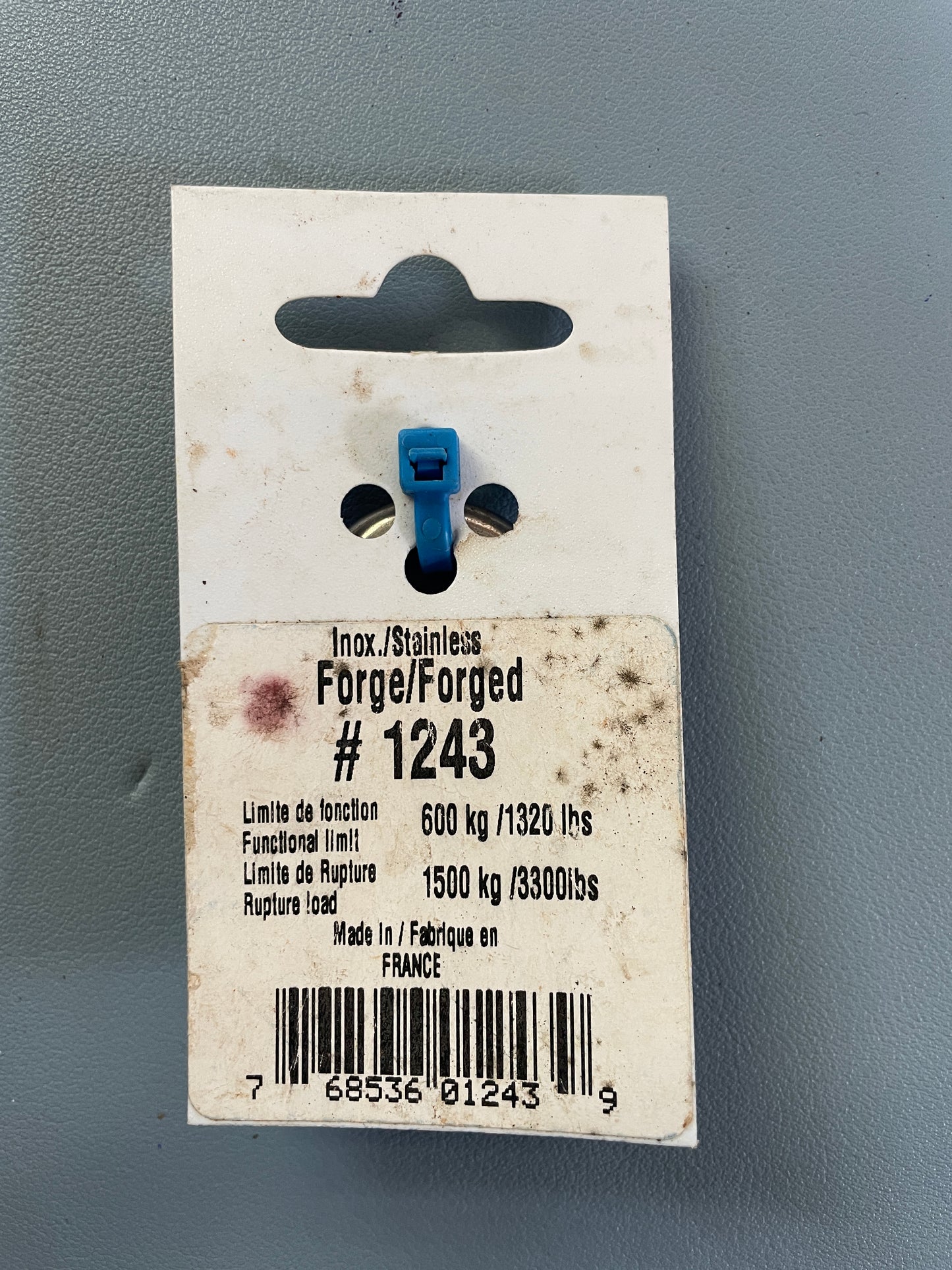 Small blue component on a white card with text and a barcode against a gray background