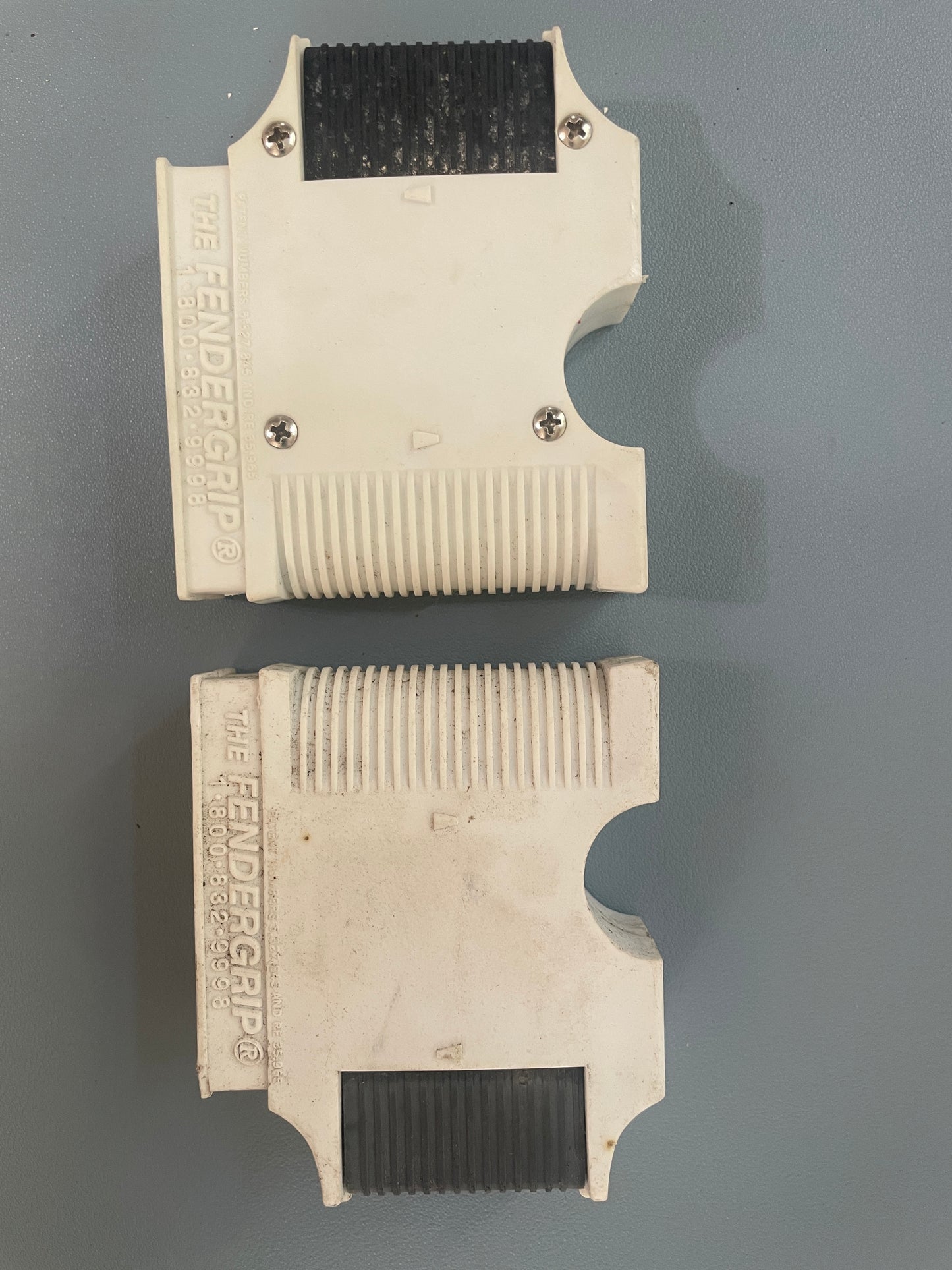 Two beige fender grips with black rubber ends on a gray background