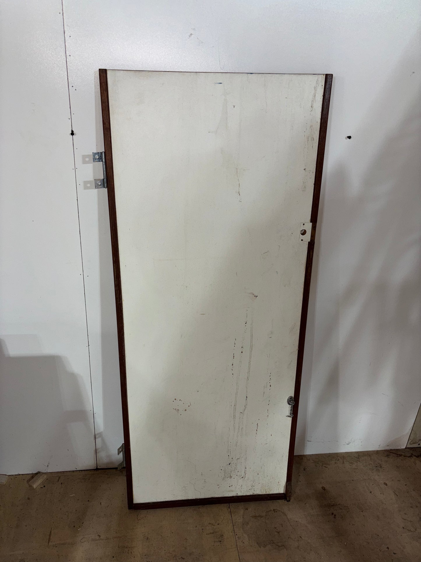 Large mirror with a wooden frame leaning against a white wall.
