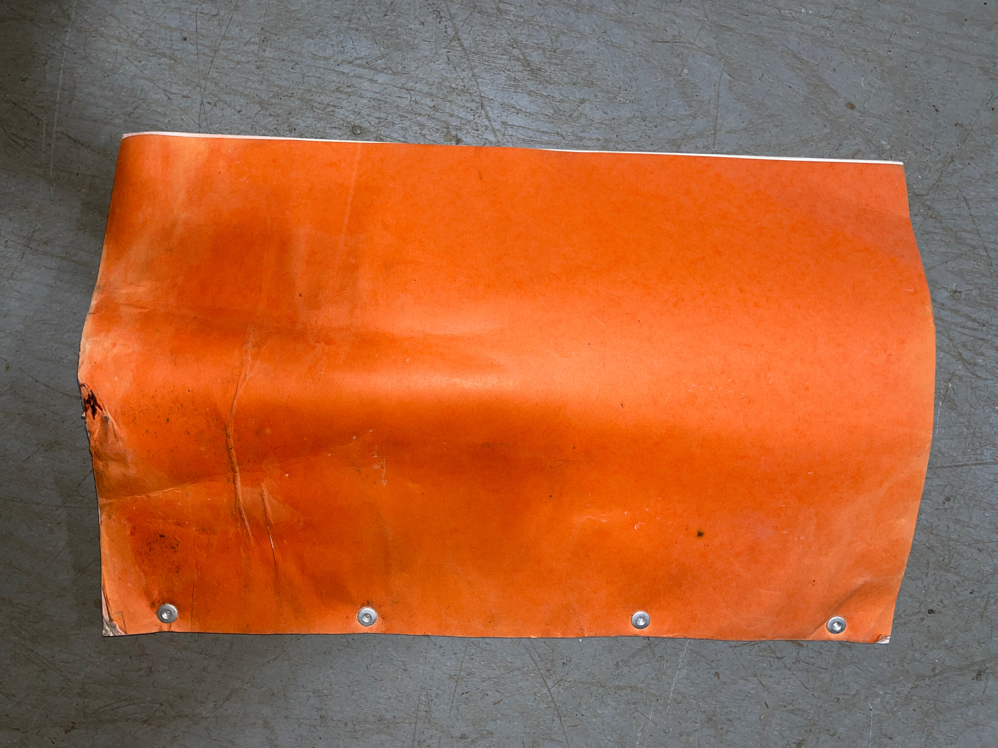 Orange leather patch with metal rivets on a gray surface