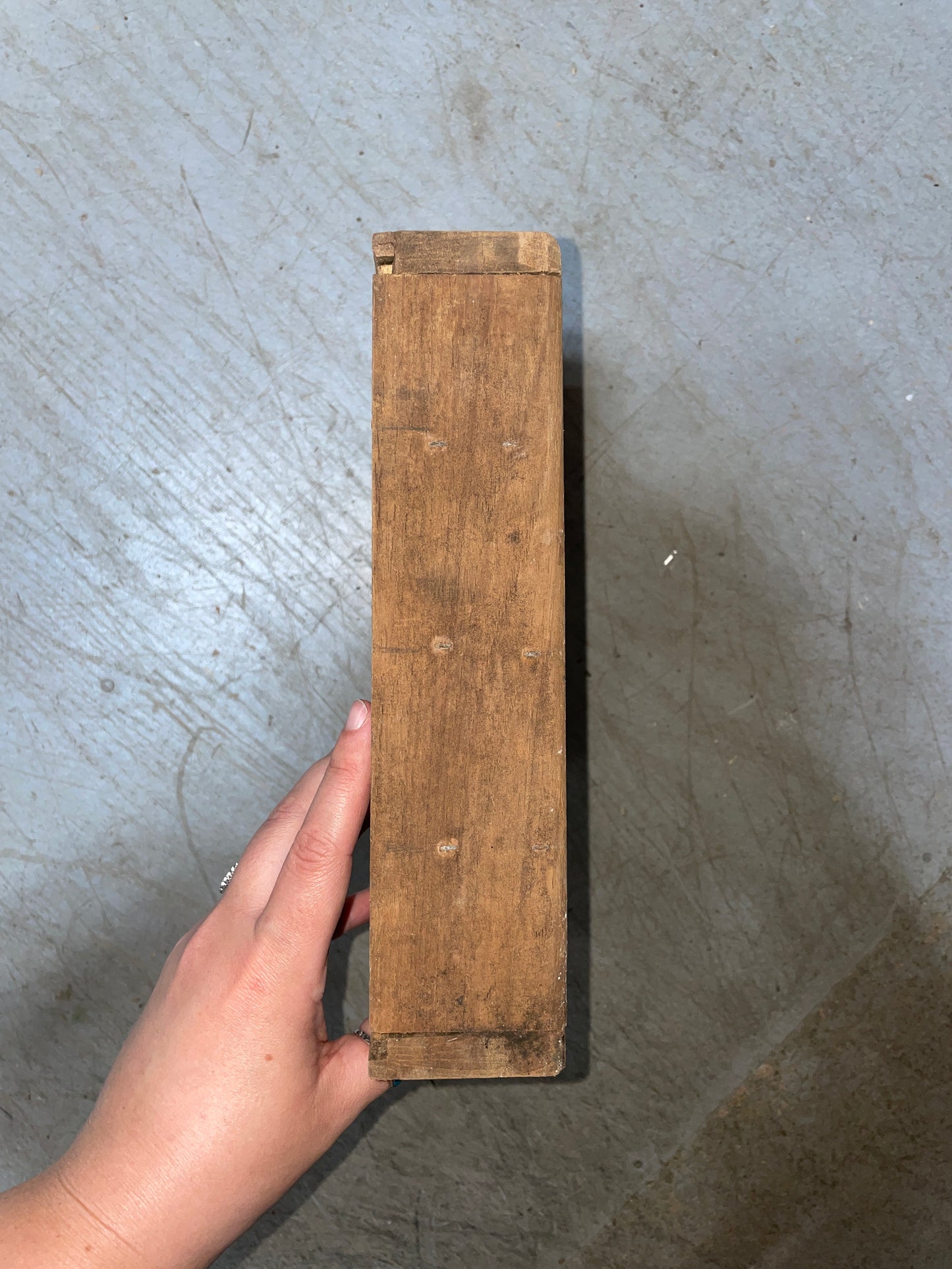 Wooden block held by a hand on a concrete floor