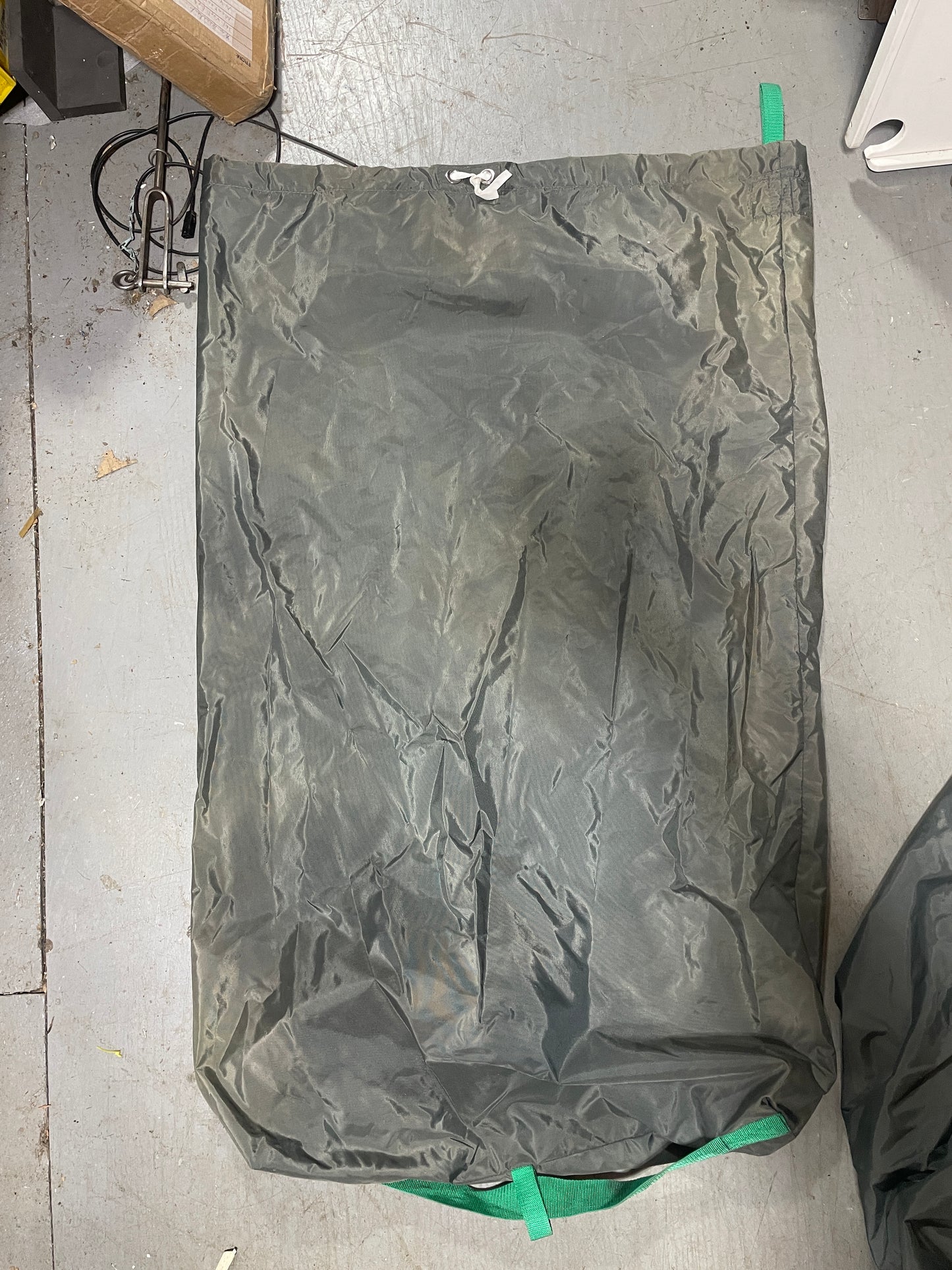 Green tarp on a concrete floor with visible wear and tear