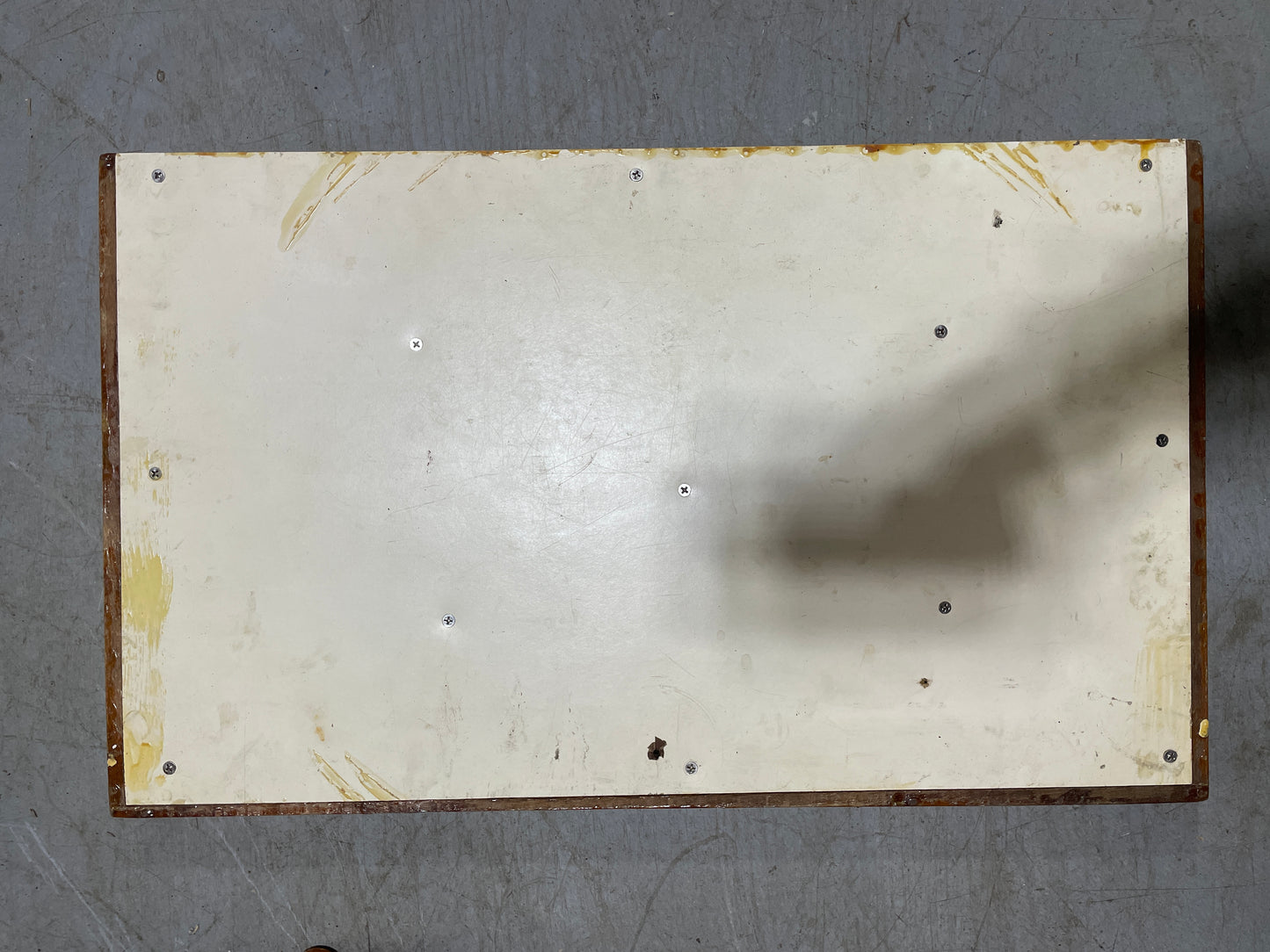 Rectangular metal plate with visible rust and wear on a gray background