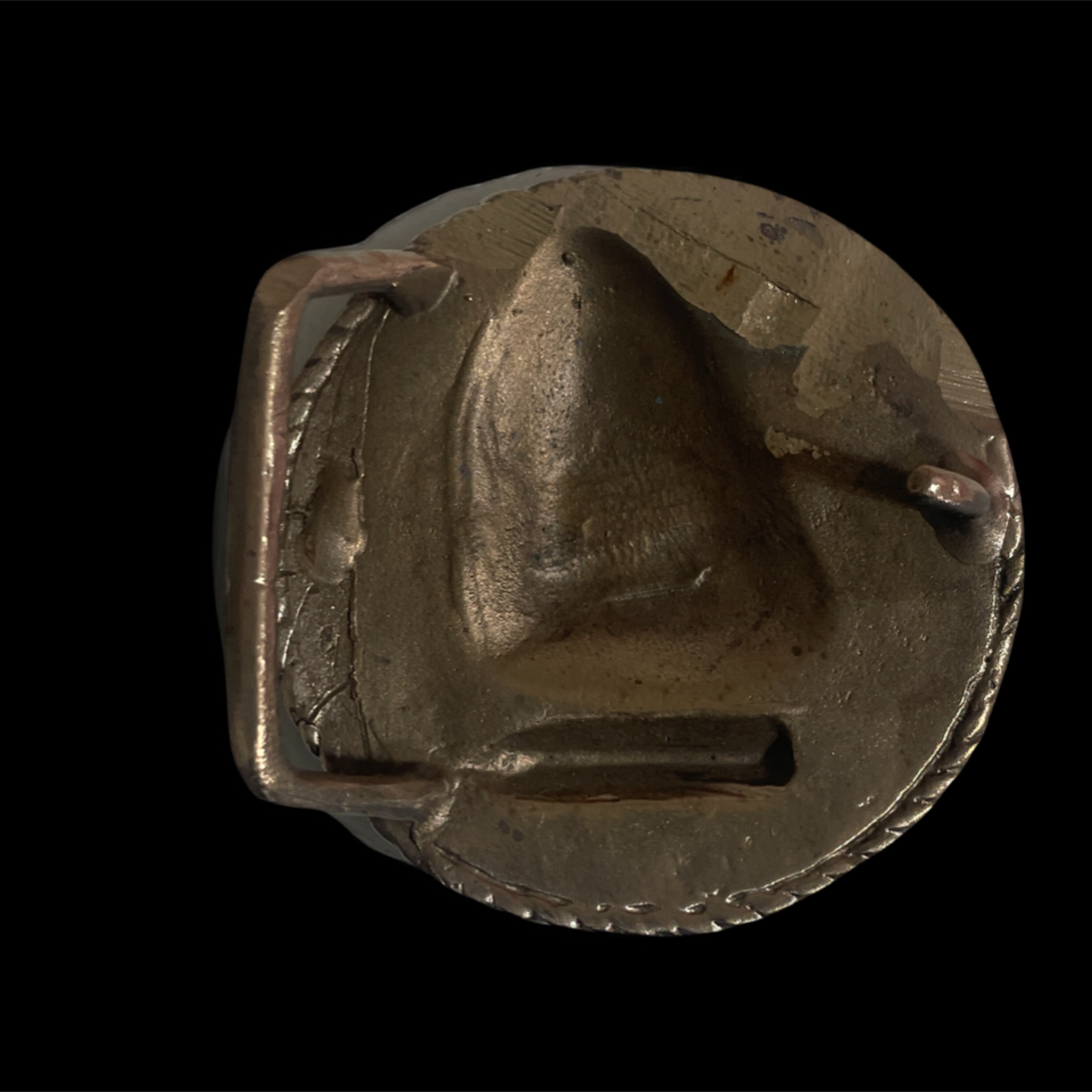 Metallic buckle with a sailboat design on a black background