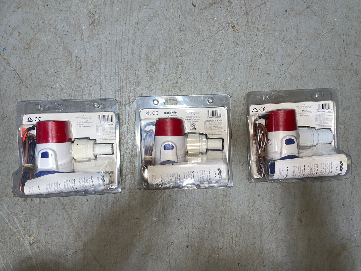 Three packages of a red and white device on a gray surface