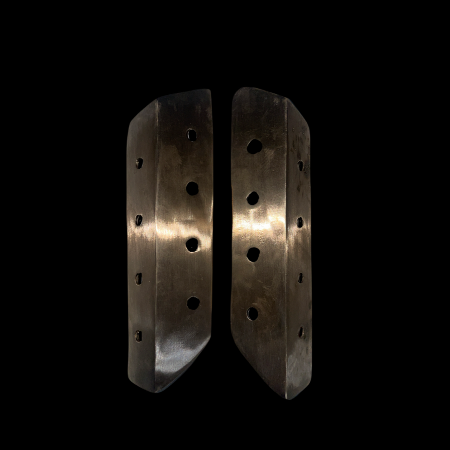 Pair of metallic knee pads with multiple holes on a black background