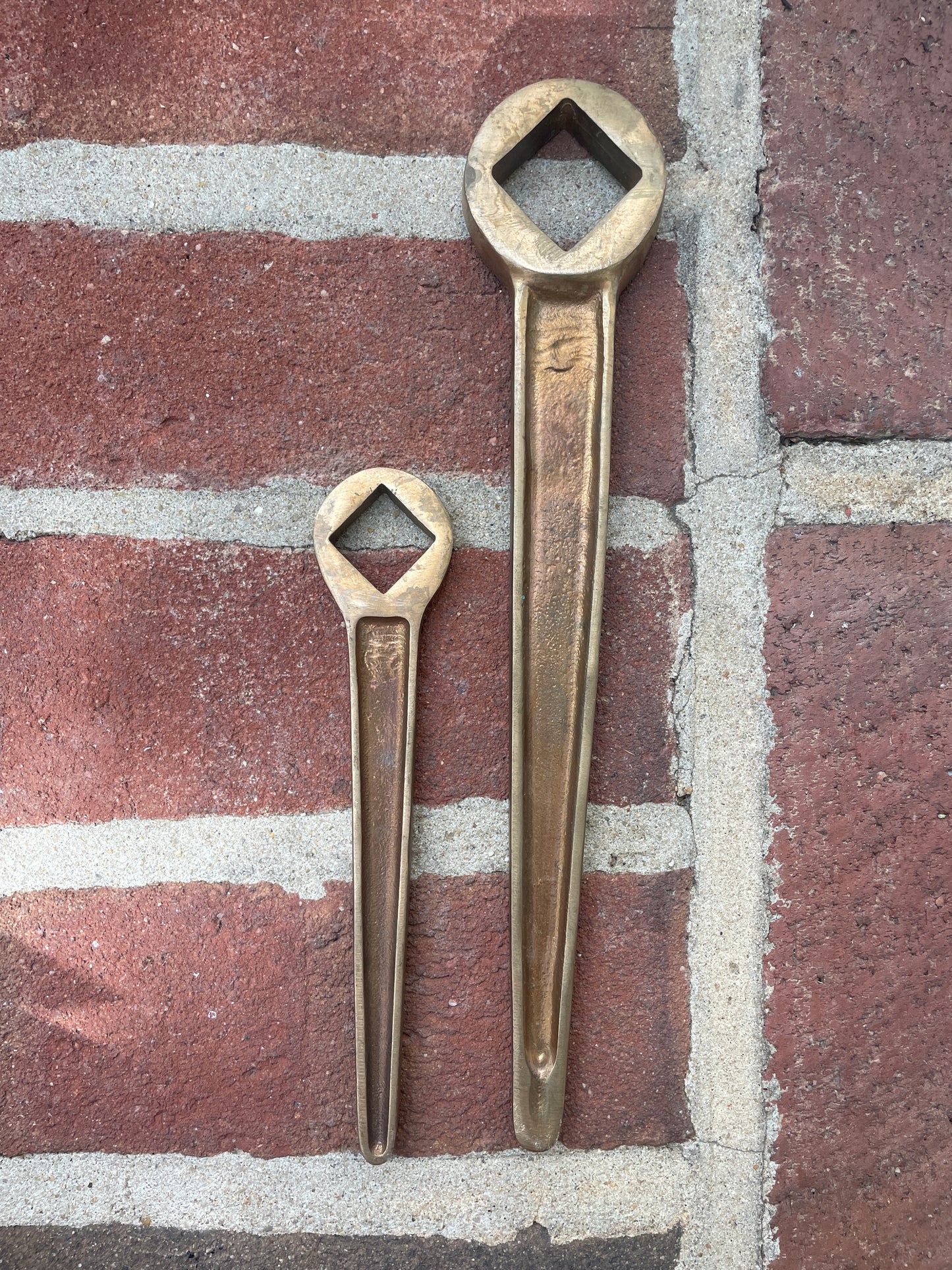 Two brass wrenches on a brick surface
