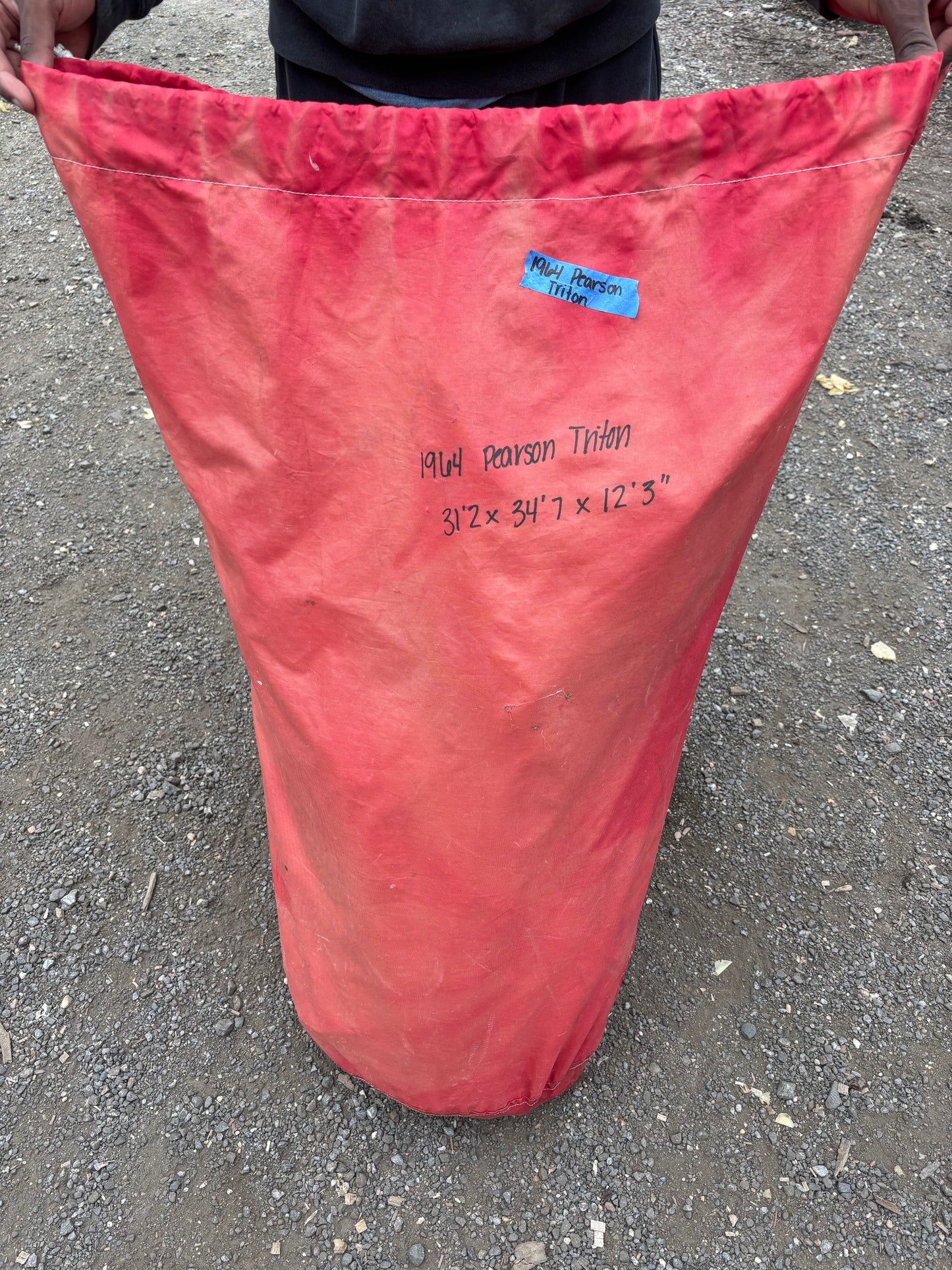 Red fabric triangle with measurements on a gray pavement