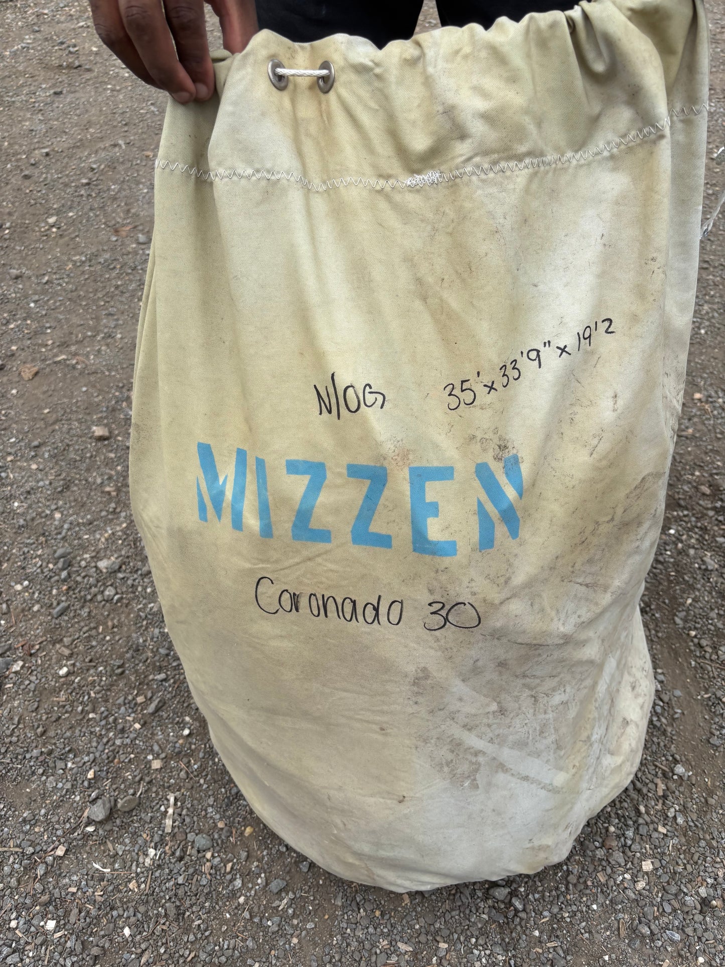 Beige bag with 'Mizzzen' branding on a concrete surface