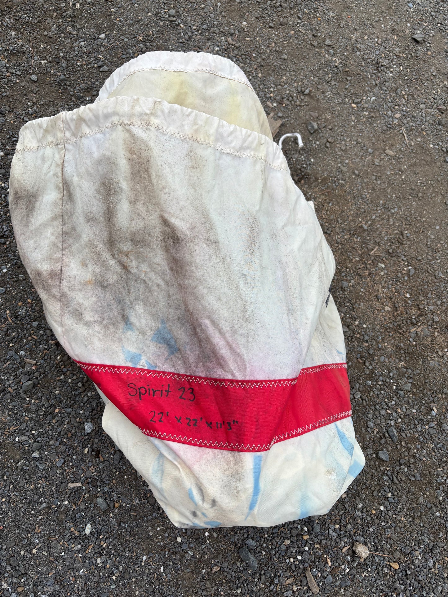 White plastic bag with red bandage on a gray pavement