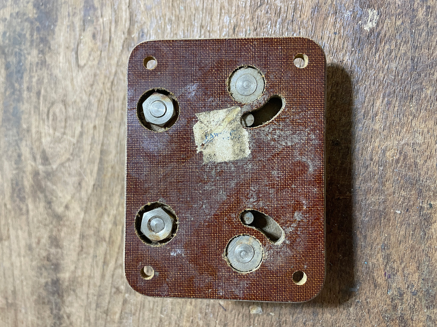 Rust-covered metal bracket with screws on a wooden surface
