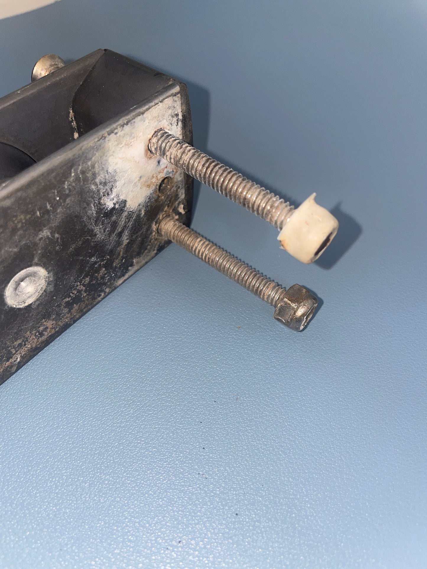 Metal bracket with two screws against a light blue wall