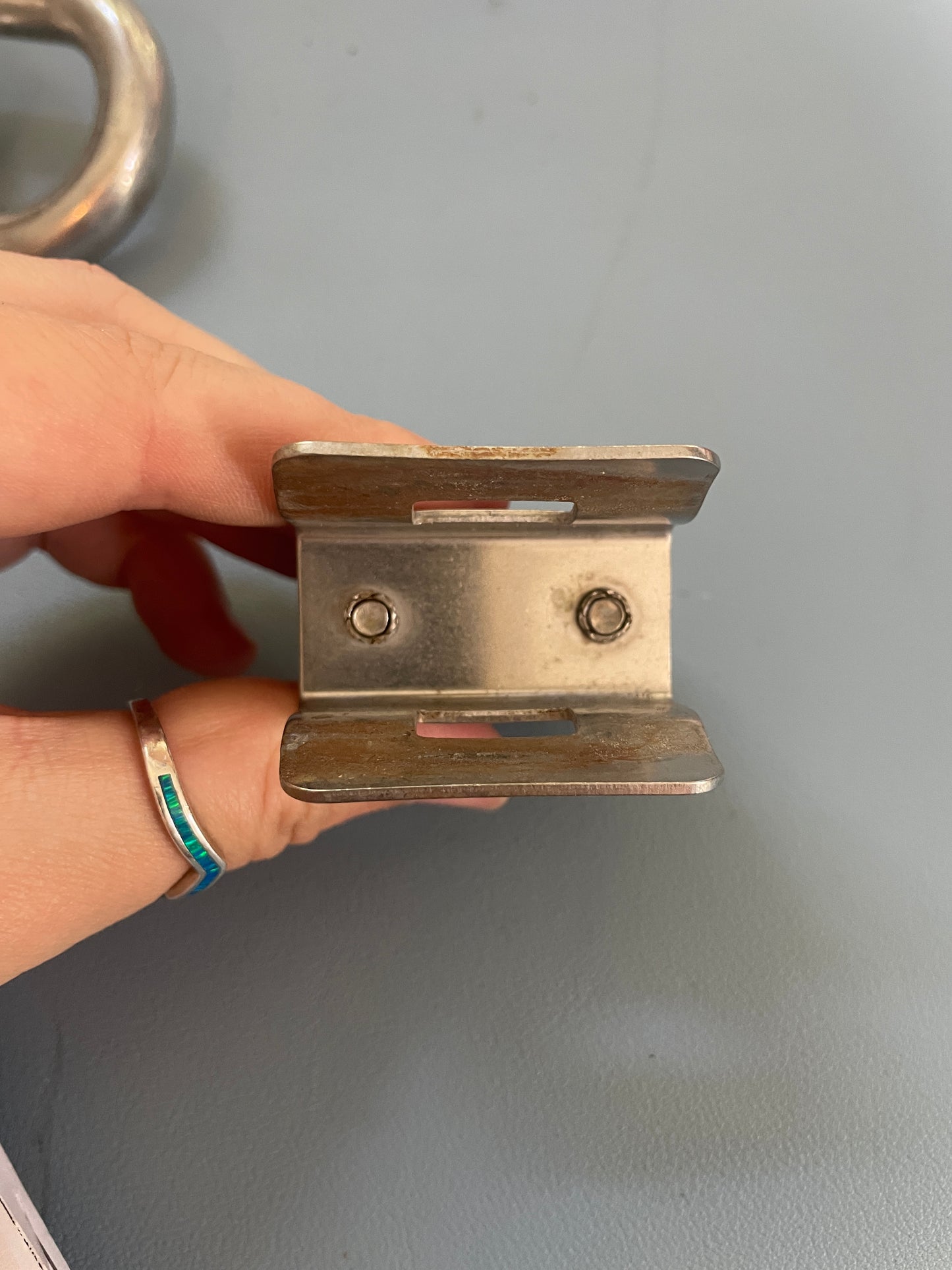 Metal bracket held by a hand against a gray background