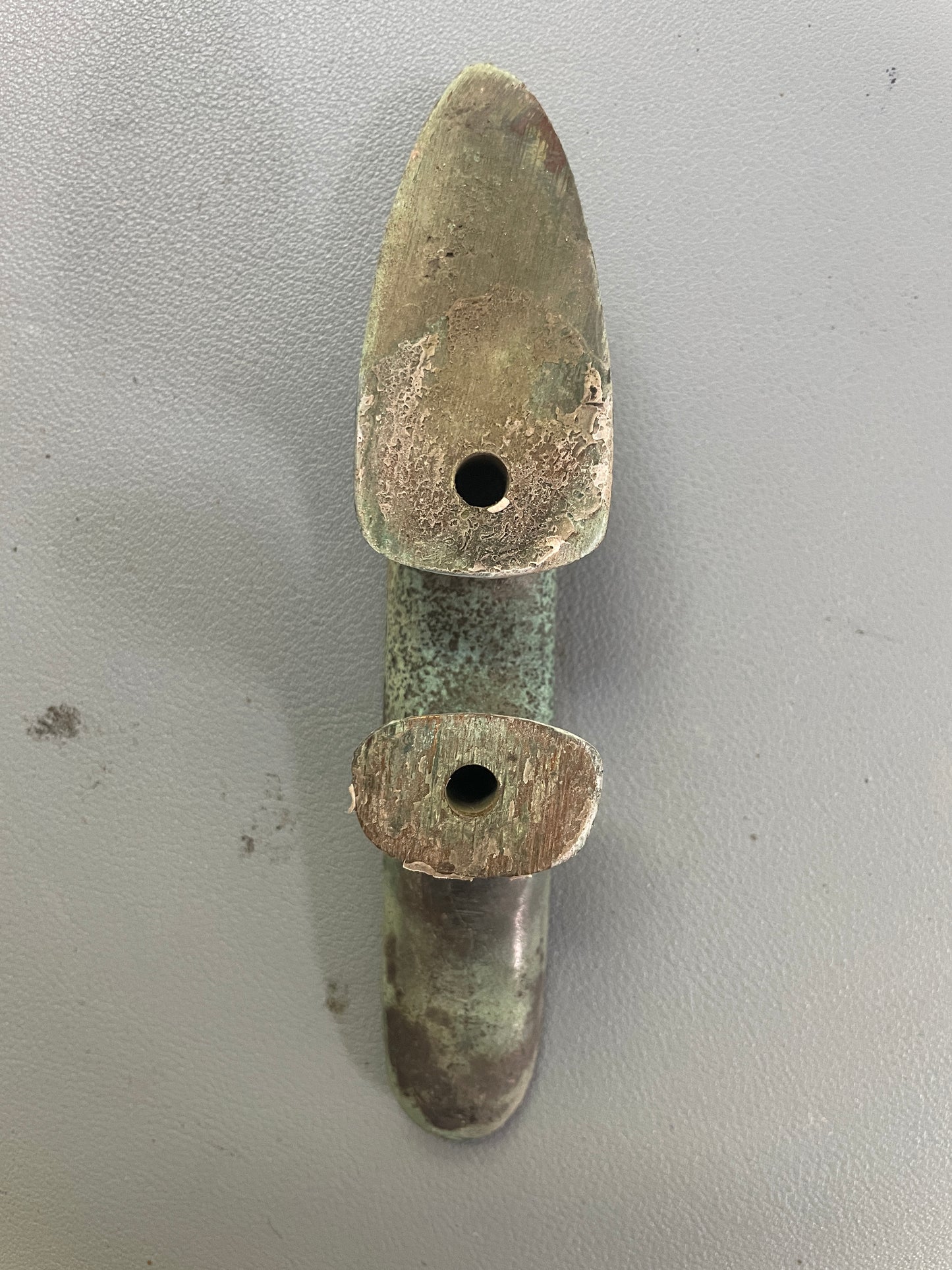 Bronze dagger with two circular holes on a gray background