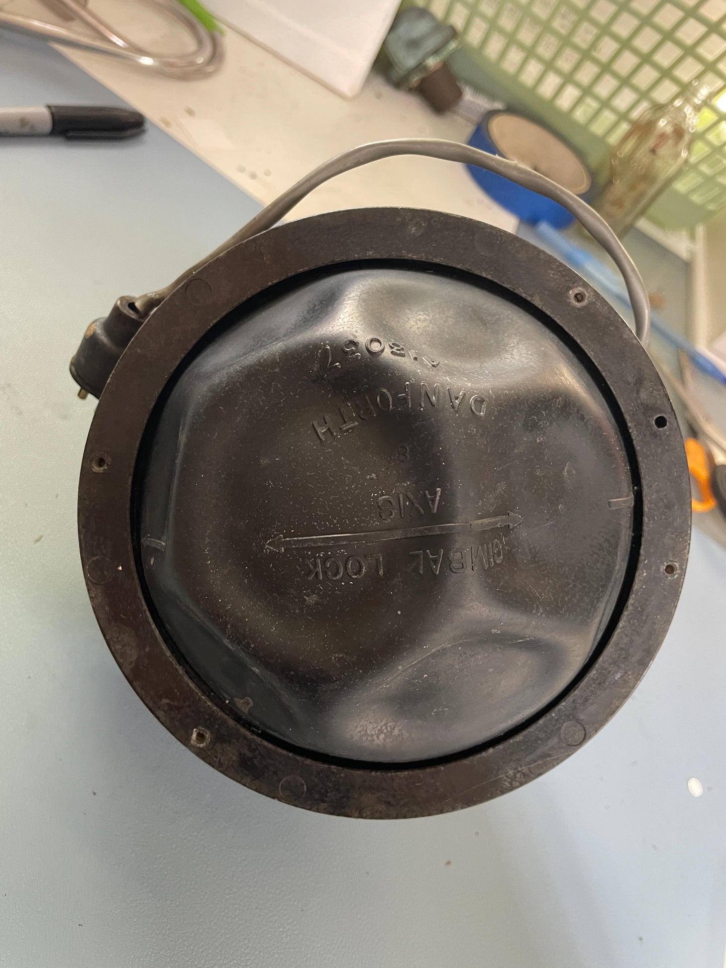 Black metal component with engraved text on a light gray surface