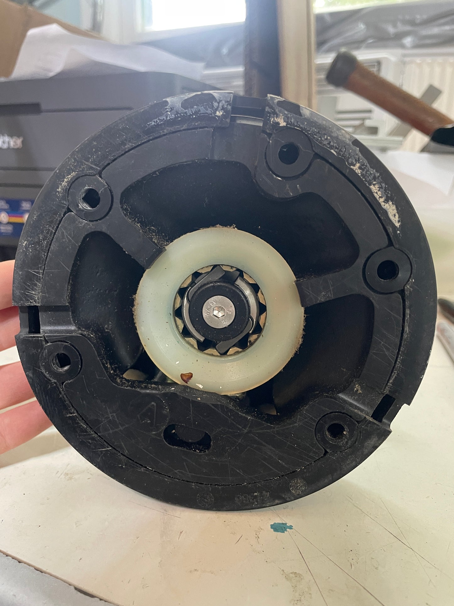 Close-up of a black mechanical component with a white roller on a blurred background