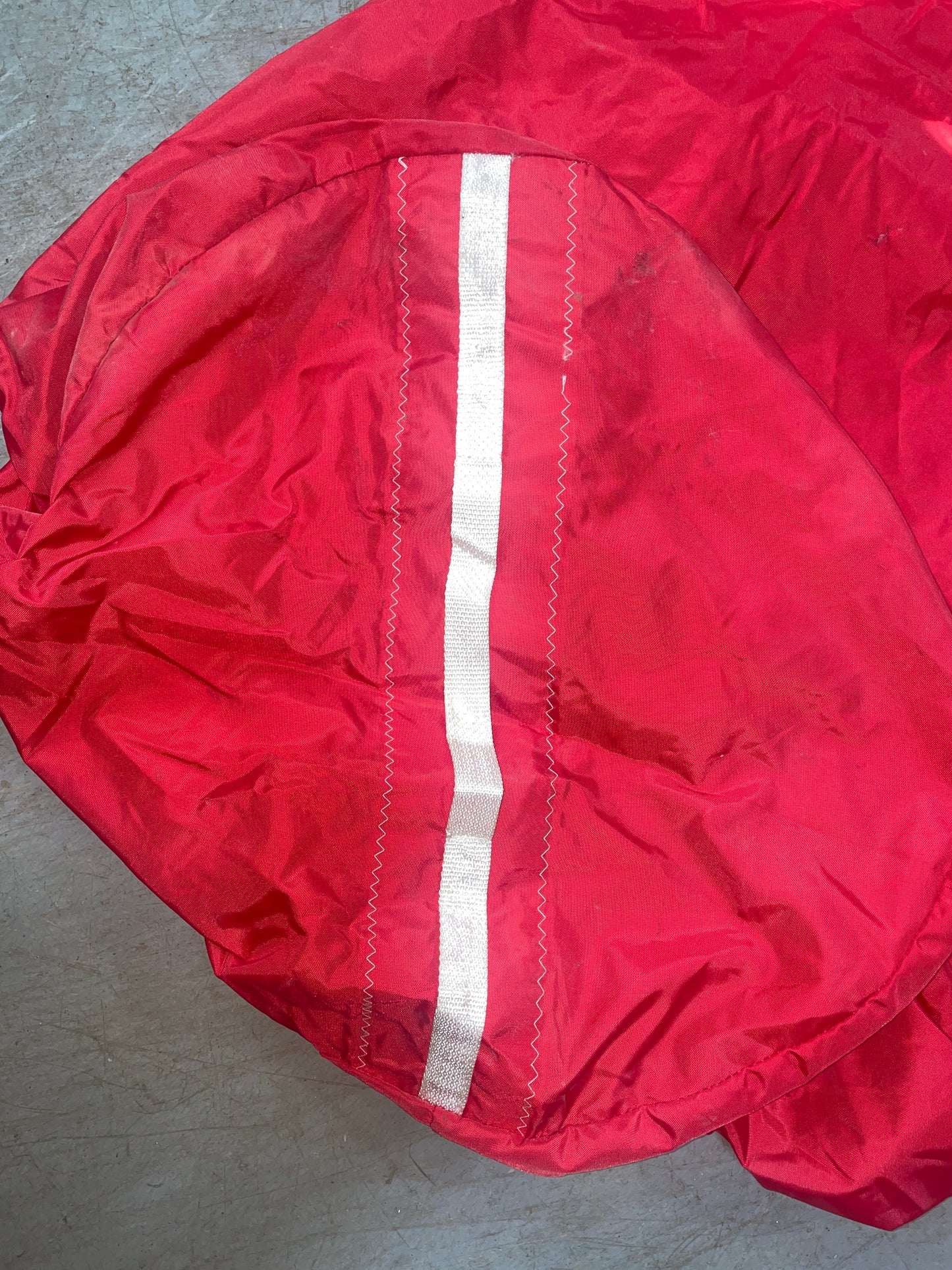 Red raincoat with reflective strip on a gray surface